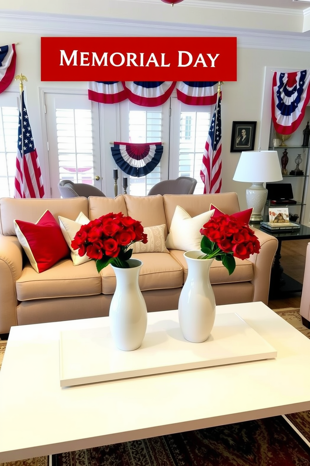 A luxurious living room decorated for Memorial Day. The room features a large, plush sofa in a neutral beige color, adorned with red, white, and blue throw pillows. A sleek, white coffee table sits in front of the sofa, holding a pair of white vases filled with vibrant red floral arrangements. American flags and patriotic banners are tastefully displayed around the room, creating a festive yet elegant atmosphere.