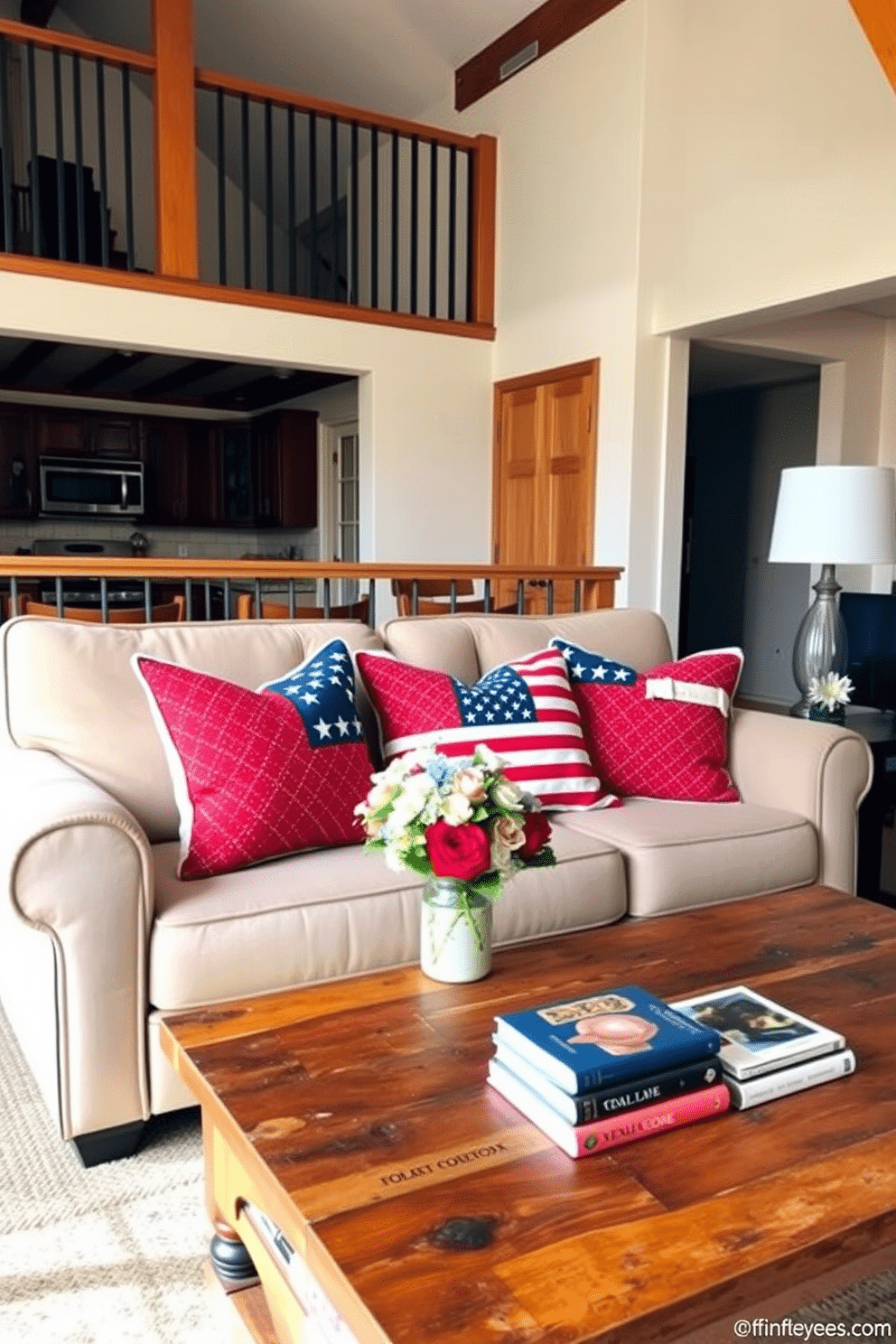 A cozy loft living room adorned with patriotic throw pillows on a plush sofa. The pillows feature vibrant red, white, and blue patterns, adding a festive touch to the space. The walls are painted in a soft neutral tone, complementing the warm wooden accents throughout the room. A rustic coffee table sits in front of the sofa, adorned with a small vase of fresh flowers and a stack of seasonal decor books.