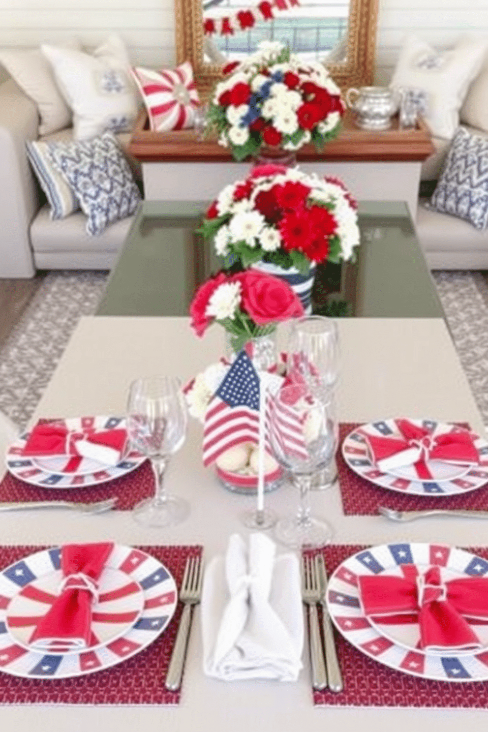 A beautifully arranged table setting features themed dinnerware in red white and blue colors. The plates are adorned with stars and stripes while elegant glassware complements the patriotic theme. For Memorial Day loft decorating ideas the space is filled with cozy seating and vibrant decorations. Soft throw pillows in seasonal colors are scattered across the furniture and a centerpiece of fresh flowers adds a festive touch.