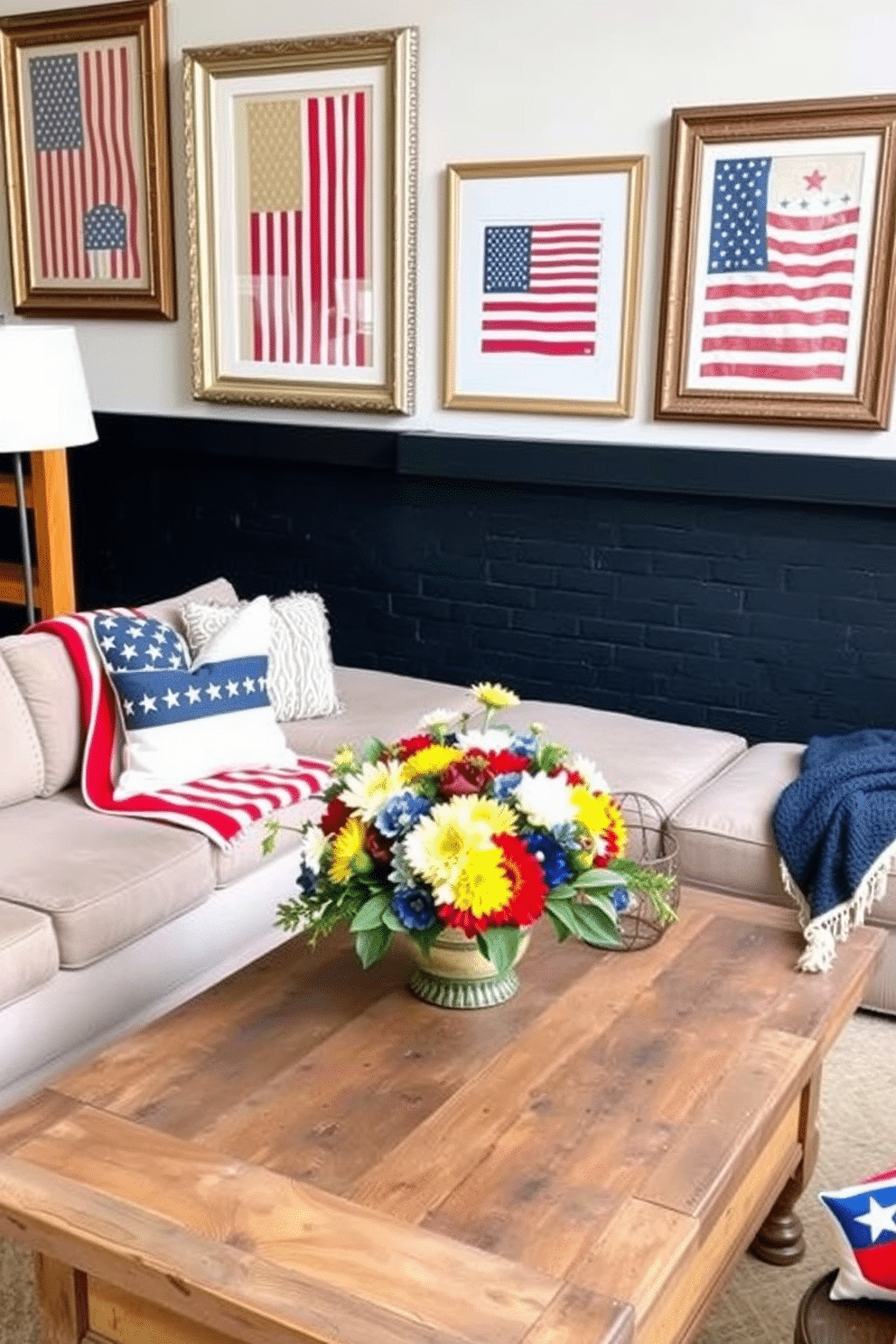 A cozy loft space decorated for Memorial Day features patriotic themed art prints in elegant frames. The walls are adorned with framed artwork showcasing red white and blue designs alongside vintage American flags. The seating area includes a plush sectional sofa draped with a stars and stripes throw blanket. A rustic wooden coffee table is topped with a centerpiece of seasonal flowers in patriotic colors.