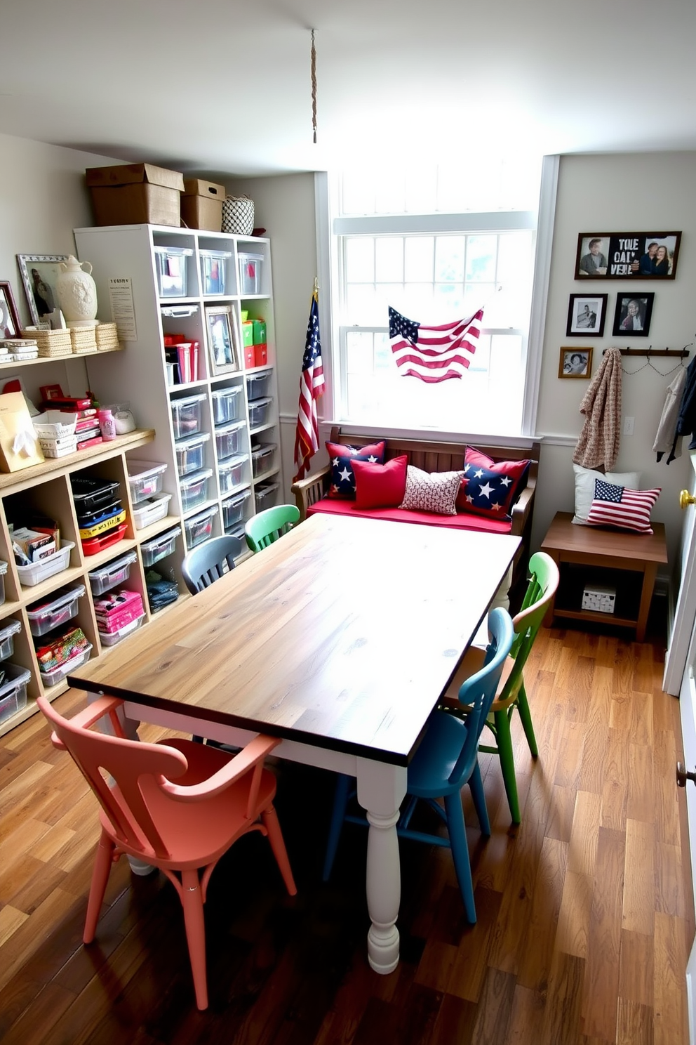 A cozy DIY craft space filled with natural light. The room features a large wooden table surrounded by colorful chairs, with various craft supplies neatly organized in clear bins on open shelves. A welcoming mudroom decorated for Memorial Day. The space includes a rustic bench with red, white, and blue cushions, and a gallery wall showcasing framed family photos and patriotic artwork.