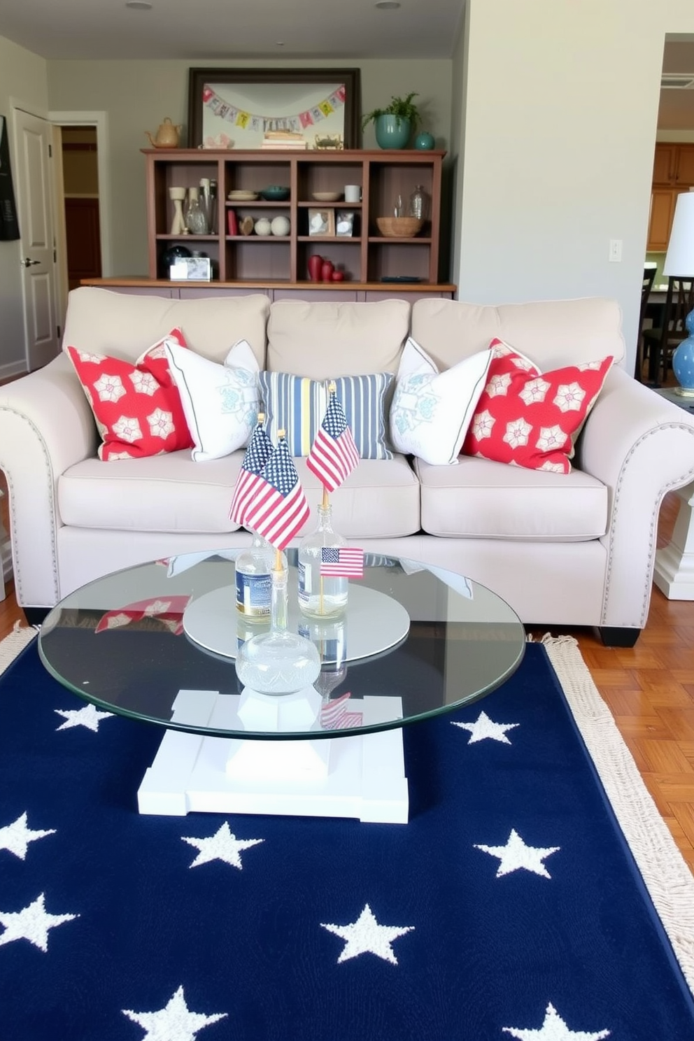 A cozy living room designed for Memorial Day celebrations. Miniature American flags are placed in decorative vases on the coffee table and side tables, adding a patriotic touch. The room features a comfortable beige sofa adorned with red, white, and blue throw pillows. A navy blue rug with white stars covers the hardwood floor, complementing the festive theme.