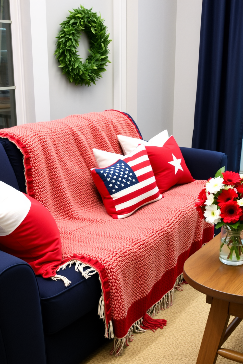 A cozy living room adorned for Memorial Day. A plush blanket in patriotic colors is draped over a navy blue sofa, adding a touch of warmth and comfort. Red, white, and blue throw pillows are arranged neatly, complementing the blanket and enhancing the festive theme. In the corner, a small wooden coffee table holds a vase filled with fresh flowers in matching colors, bringing a sense of celebration to the space.