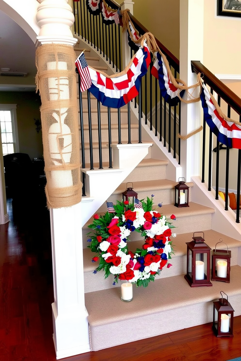 A grand staircase decorated for Memorial Day, featuring a railing wrapped in natural burlap and rustic twine. Red, white, and blue bunting is draped along the railing, complemented by small American flags tucked into the twine. At the base of the staircase, a large decorative wreath made of red, white, and blue flowers is placed. Patriotic-themed lanterns with candles sit on each step, creating a warm and inviting ambiance.