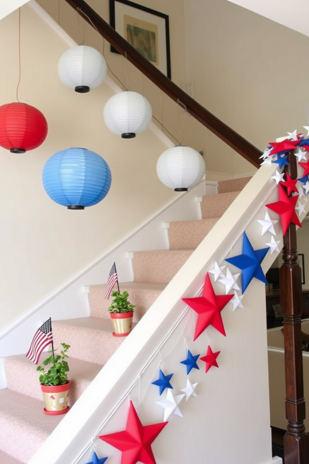 A staircase decorated for Memorial Day, featuring red, white, and blue hanging paper lanterns. The lanterns are strung along the banister, creating a festive and patriotic atmosphere. The staircase itself is adorned with small American flags placed in potted plants on each step. Additionally, a garland of stars in matching colors drapes elegantly from the handrail, enhancing the celebratory theme.