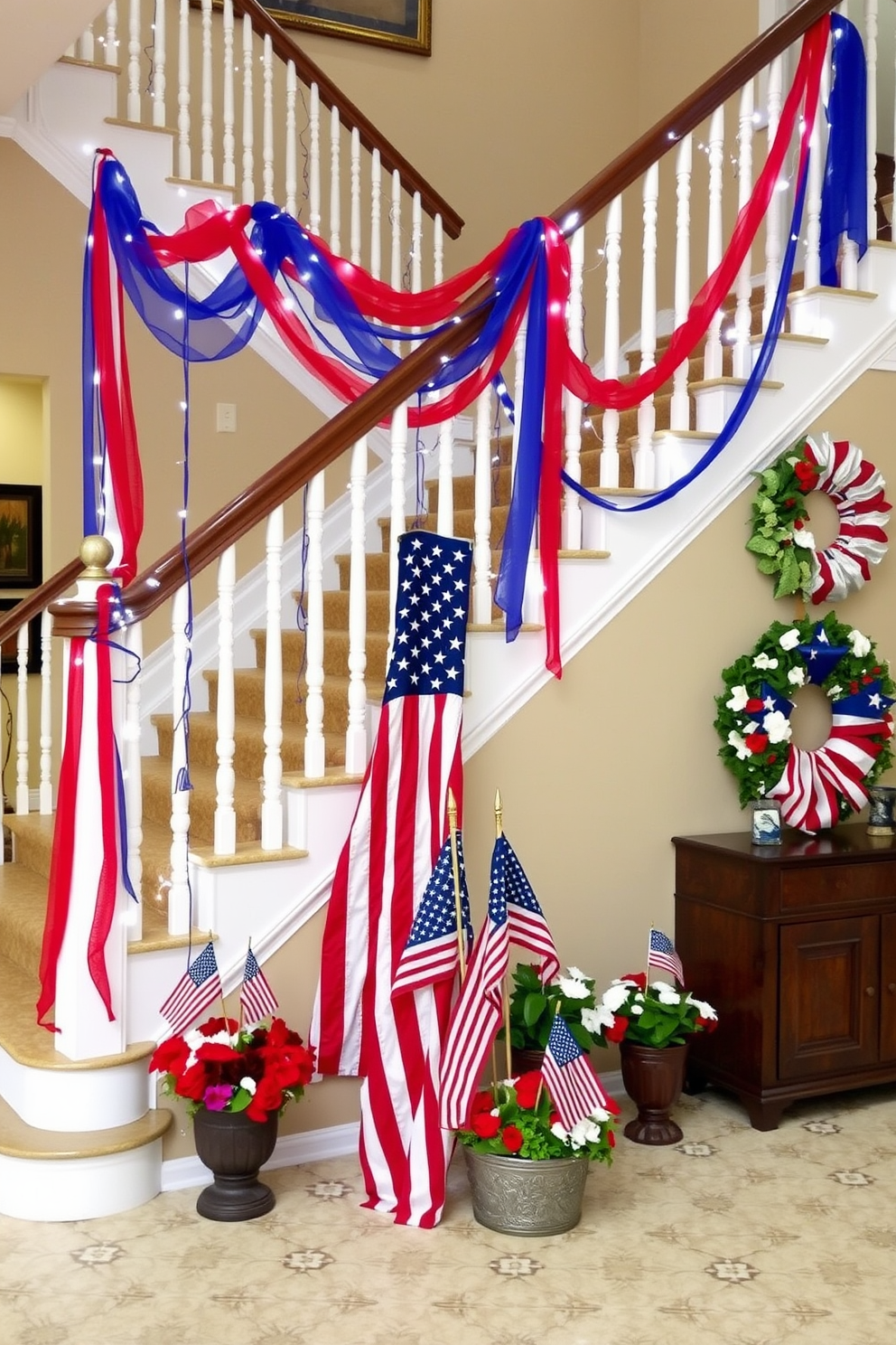 A grand staircase adorned for Memorial Day. Red and blue streamers cascade down the banister, intertwined with white fairy lights, creating a patriotic display. At the base of the stairs, a large American flag is draped elegantly, flanked by potted plants with red, white, and blue flowers. Small American flags are placed in the planters, and a decorative wreath featuring stars and stripes hangs on the wall beside the staircase.