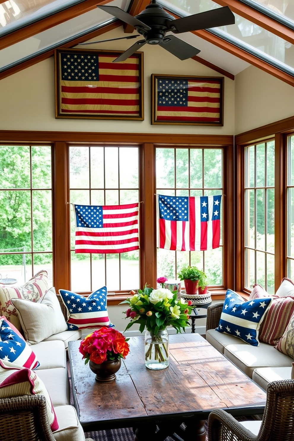 A sunroom filled with natural light features vintage American flags displayed in elegant wooden frames on the walls. The decor includes comfortable seating with patriotic-themed cushions and a rustic coffee table adorned with seasonal flowers.