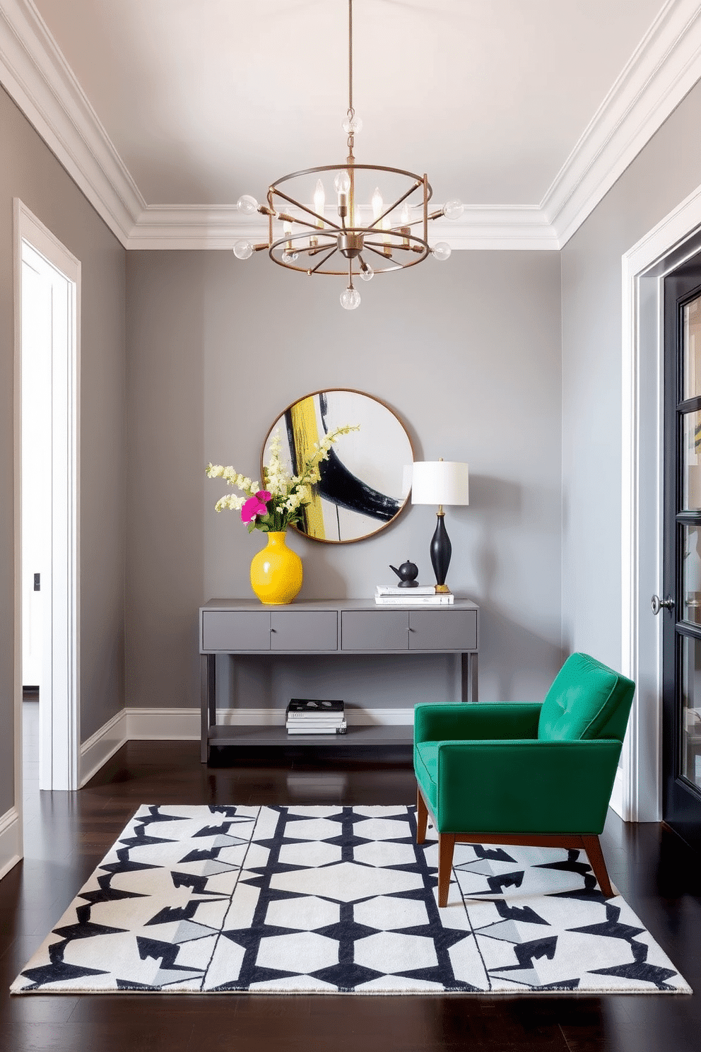 A stylish foyer featuring a monochromatic color scheme with pops of vibrant color. The walls are painted in a soft gray, complemented by a sleek console table in a matching hue, adorned with a bright yellow vase and fresh flowers. A geometric patterned rug in shades of black and white anchors the space, while a striking mid-century modern chandelier hangs above, casting a warm glow. A pair of minimalist chairs, upholstered in a rich emerald green, flanks the entrance, inviting guests into the home.