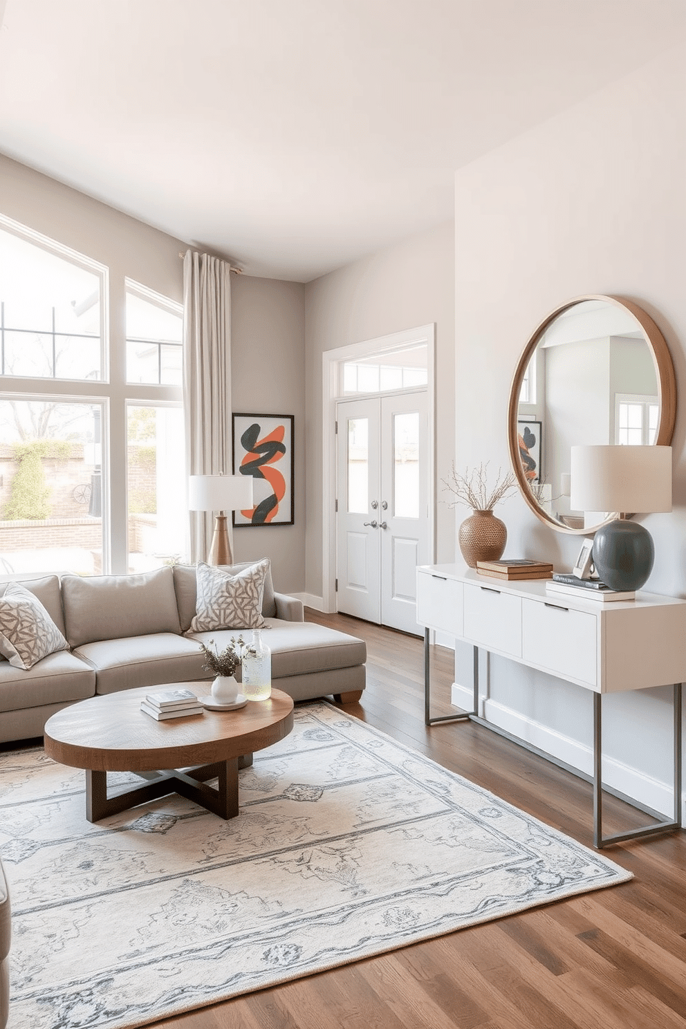 A multi-functional space with a cozy seating area features a plush sectional sofa in a soft gray fabric, complemented by a round coffee table made of reclaimed wood. A stylish area rug anchors the seating, while large windows allow natural light to flood the room, enhancing the inviting atmosphere. The modern foyer design showcases a sleek console table with a minimalist design, topped with decorative accents like a contemporary lamp and a few curated books. Bold artwork adorns the walls, and a statement mirror reflects the space, creating an open and welcoming entryway.