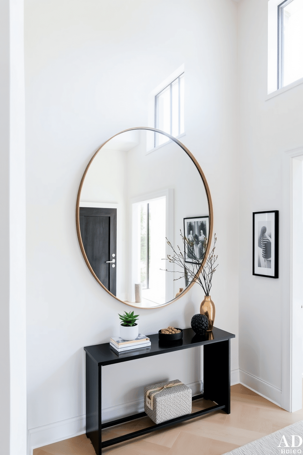 A modern foyer features a large round mirror that enhances the sense of space and depth, reflecting natural light throughout the area. The walls are adorned with sleek, minimalist artwork, and a stylish console table sits beneath the mirror, topped with decorative items and a small potted plant.