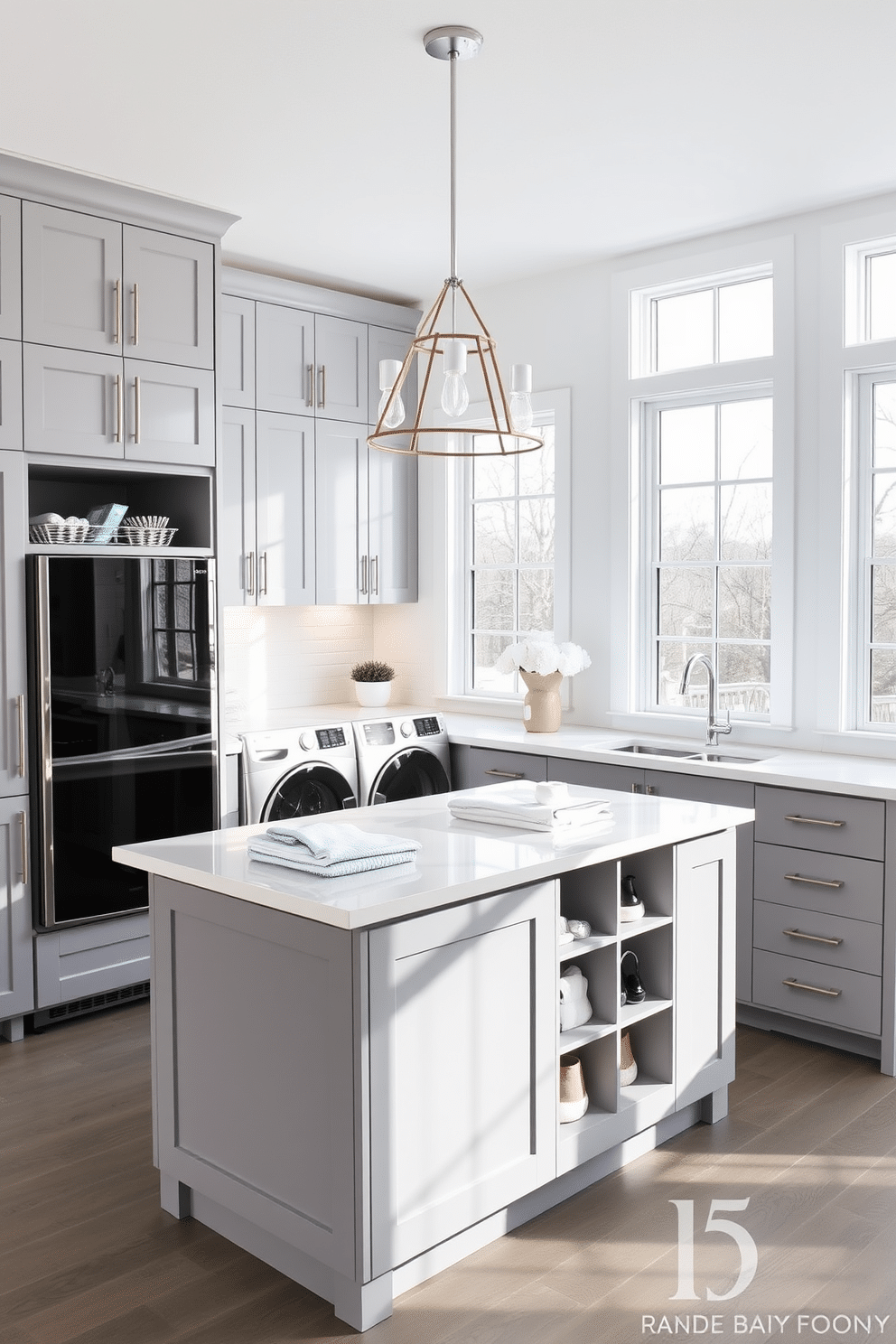 A functional island designed for folding and sorting laundry, featuring ample surface space and built-in storage compartments. The island is surrounded by sleek cabinetry in a soft gray finish, with a contemporary light fixture hanging above to illuminate the workspace. The laundry room showcases a combination of modern appliances, including a front-loading washer and dryer, seamlessly integrated into the cabinetry. Large windows allow natural light to flood the space, enhancing the bright, airy atmosphere with a fresh white and pastel color palette.