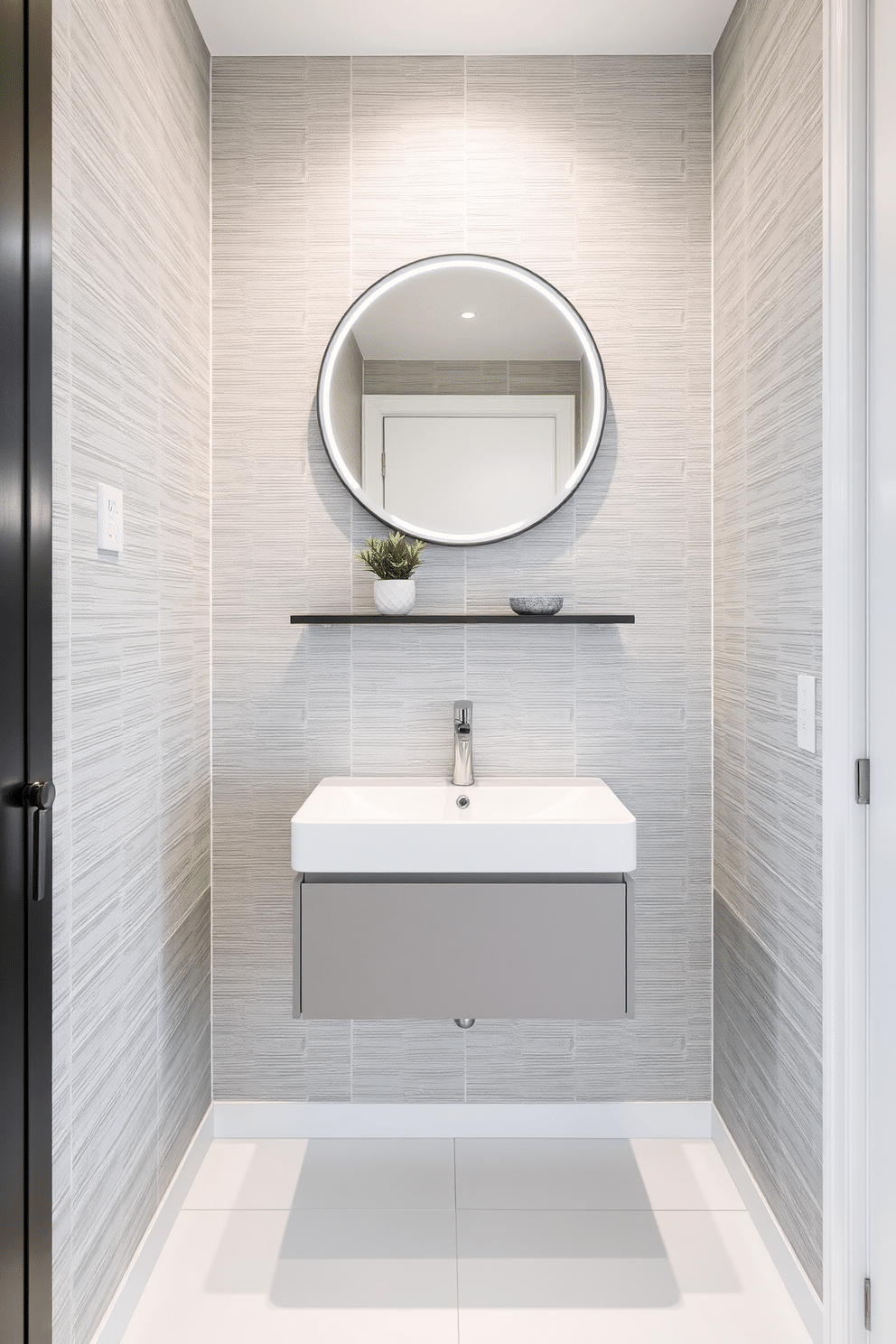 A modern powder room featuring a sleek wall-mounted sink with a minimalist faucet and a floating shelf above for decorative items. The walls are adorned with textured wallpaper in a soft gray, while the floor is finished with large-format white tiles that create an illusion of space. Incorporating a round mirror with integrated lighting above the sink enhances the room's brightness. A small potted plant sits on the shelf, adding a touch of greenery to the sophisticated design.