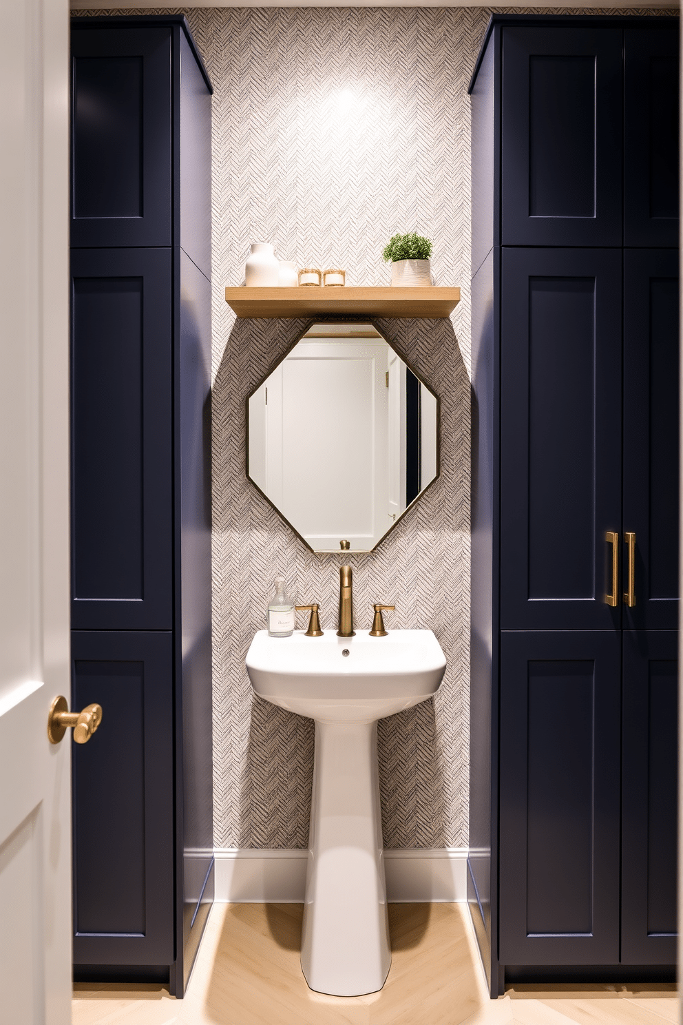 A modern powder room featuring custom cabinetry that maximizes storage while maintaining a sleek aesthetic. The cabinetry is finished in a rich navy blue with brass hardware, complemented by a stylish floating shelf above for decorative items. The space includes a chic pedestal sink with a striking geometric mirror above it. Soft ambient lighting highlights the textured wallpaper, creating an inviting atmosphere perfect for guests.