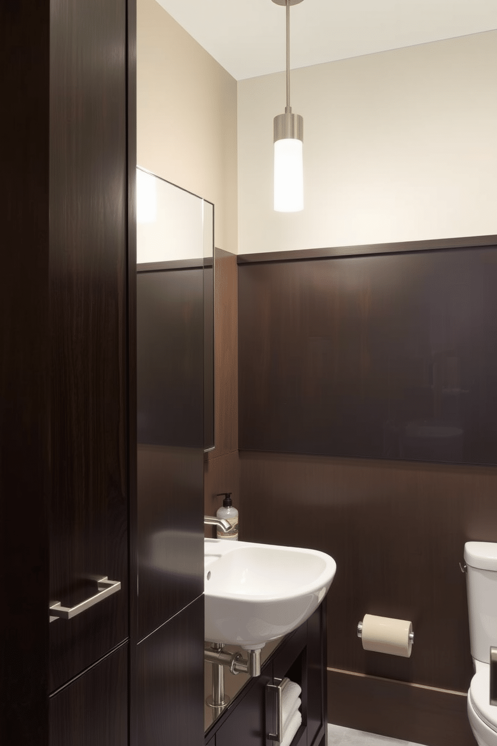 A modern powder room featuring dark wood cabinetry with brushed nickel handles. The space is illuminated by sleek pendant lights, highlighting the elegant design elements throughout.