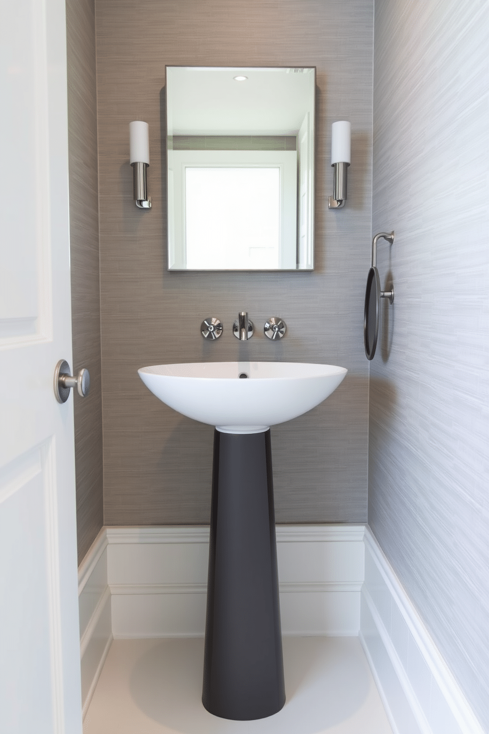 A contemporary powder room features a sleek pedestal supporting a stylish vessel sink. The walls are adorned with textured wallpaper in a soft gray, complemented by polished chrome fixtures and a minimalist mirror above the sink.