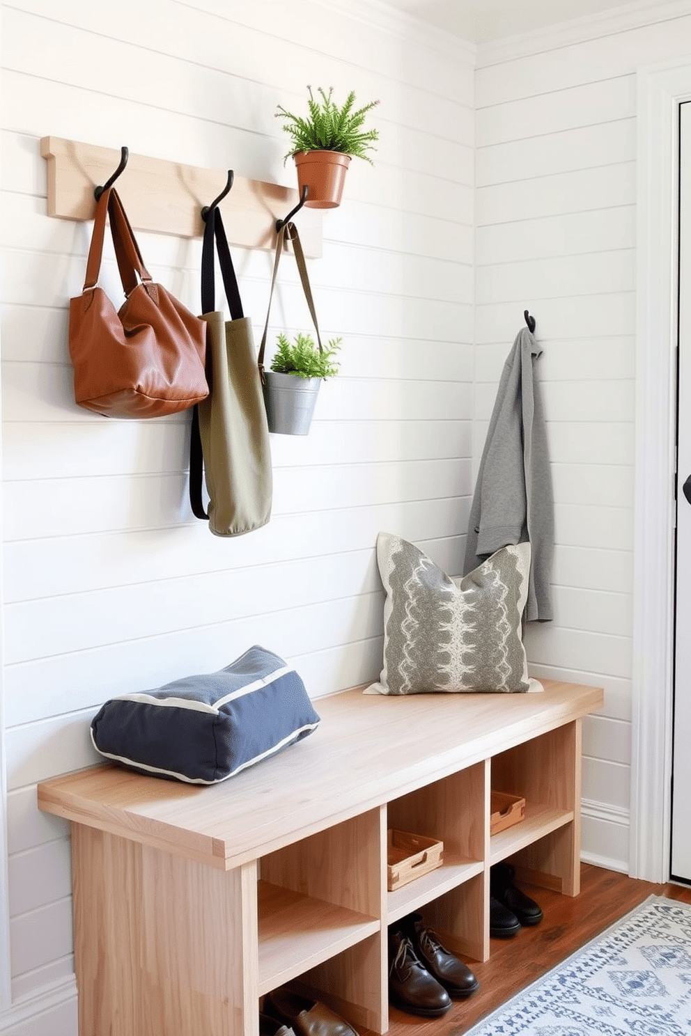 A narrow bench designed for small entryways features a sleek, minimalist profile with a light wood finish and soft cushioning for comfort. Above the bench, wall-mounted hooks provide a practical solution for hanging coats and bags, while a small potted plant adds a touch of greenery. For the mudroom bench, envision a sturdy, built-in design with ample storage underneath for shoes and outdoor gear. The bench is complemented by a durable, weather-resistant cushion and a backdrop of shiplap walls painted in a soft, inviting color.