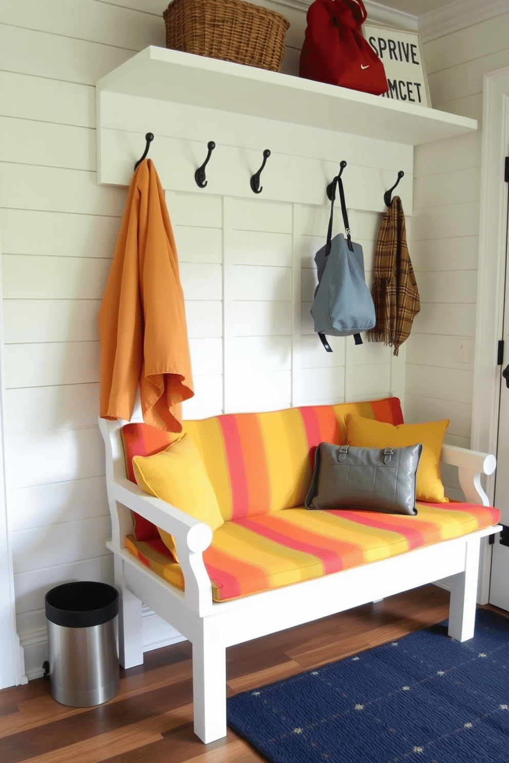 A cheerful mudroom features a spacious bench upholstered in vibrant, colorful fabric that adds a playful touch. The bench is positioned against a backdrop of shiplap walls, with hooks above for hanging coats and bags, creating an inviting and functional entryway.