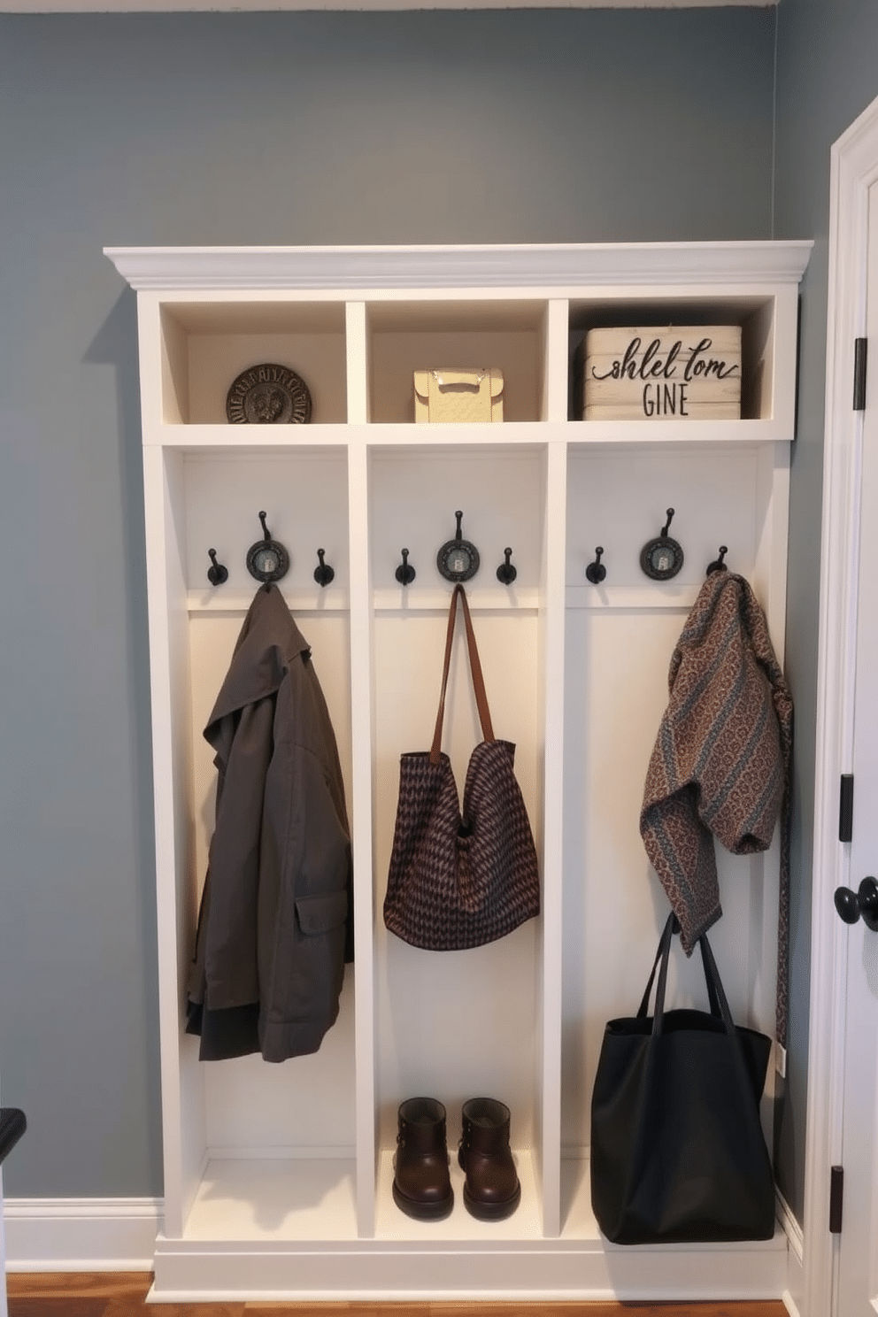 A stylish mudroom features wall-mounted cubbies with hooks above, providing a practical and organized space for coats and bags. The cubbies are painted in a soft, neutral color, and each hook is adorned with decorative accents, creating a welcoming and functional entrance.