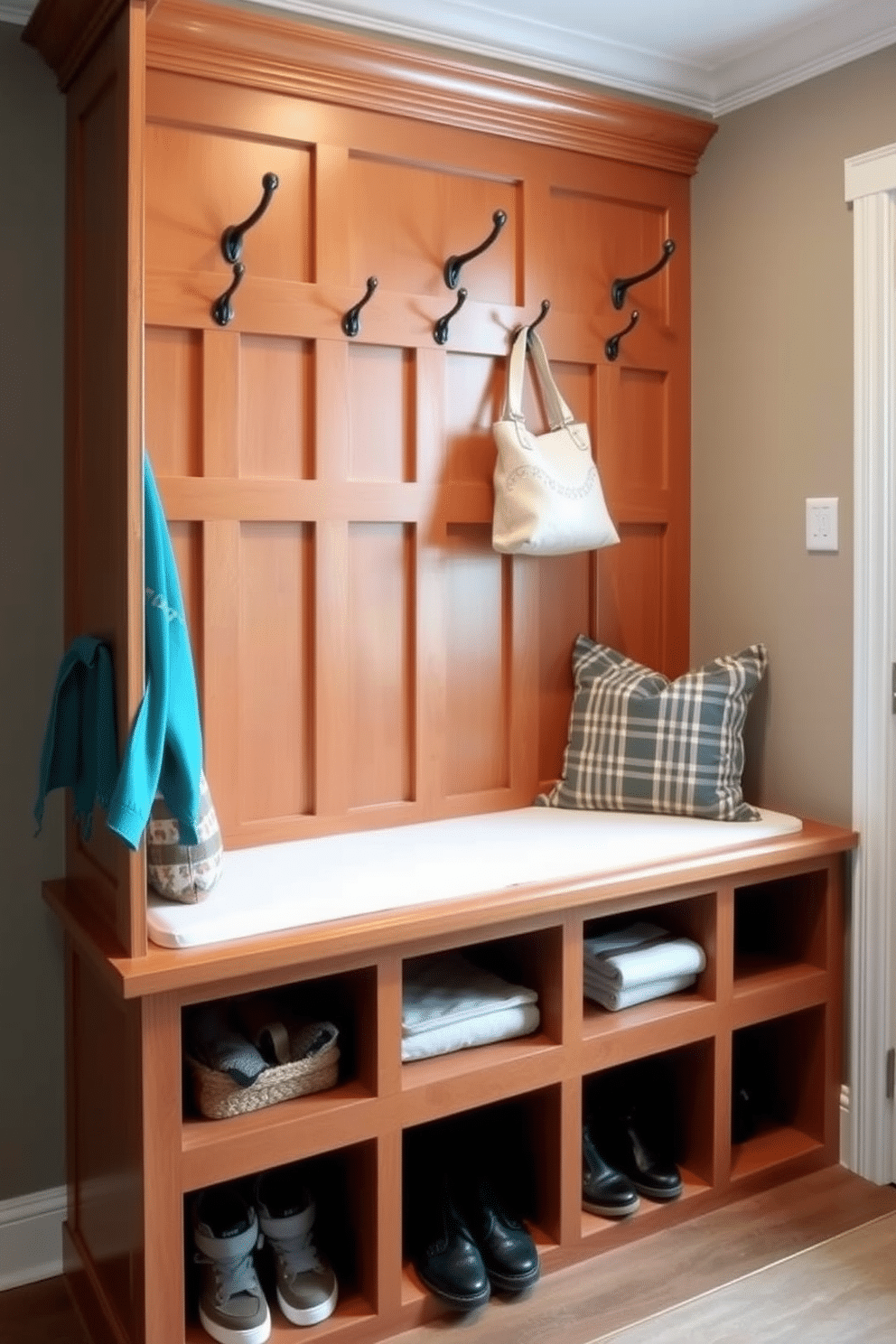 A custom built corner bench with integrated hooks provides a functional and stylish solution for any mudroom. The bench features a warm wood finish, complemented by soft cushions, while the hooks are arranged neatly above for easy access to coats and bags. The cubby design incorporates spacious compartments beneath the bench, ideal for storing shoes and outdoor gear. Each cubby is framed with decorative molding, enhancing the overall aesthetic while maintaining a clean and organized look.