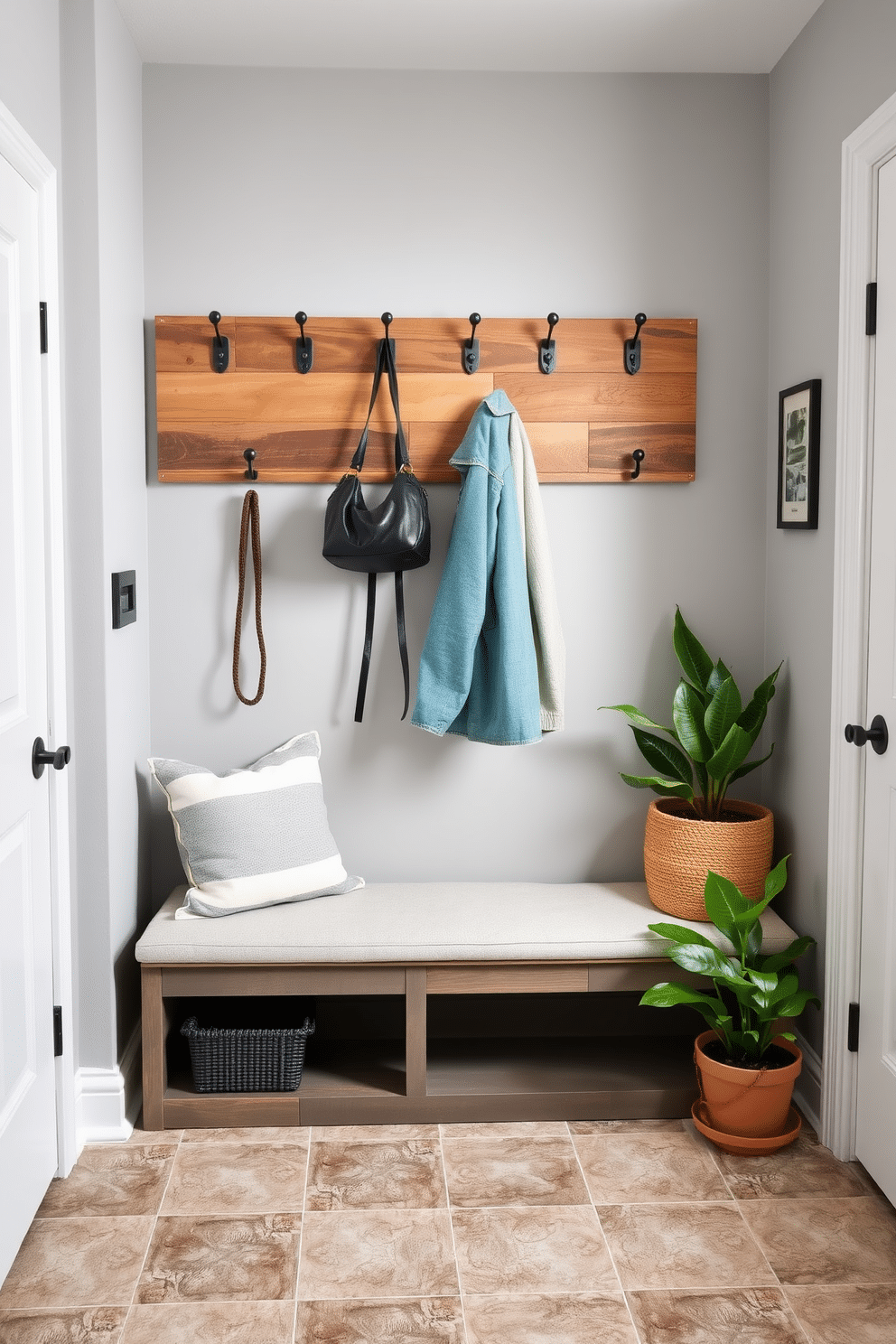 A stylish mudroom featuring a wall-mounted folding table, perfect for maximizing space. The table is crafted from reclaimed wood, with sleek metal brackets, and is adorned with decorative hooks above for hanging coats and bags. The floor is covered in durable, patterned tile that complements the soft gray walls. A cozy bench with storage underneath offers a welcoming touch, while potted plants add a splash of greenery to the design.