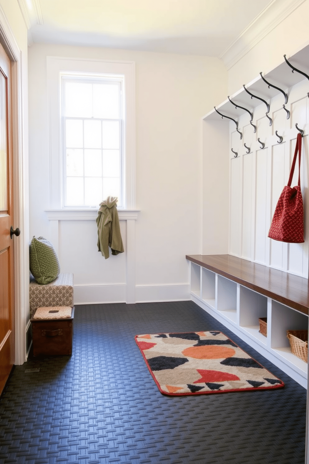 A functional mudroom with durable flooring designed for heavy foot traffic. The space features interlocking rubber tiles in a deep gray shade, providing both resilience and style, while built-in benches with storage cubbies line one wall for easy organization. Natural light floods the room through a large window, illuminating the walls painted in a soft, welcoming white. A row of hooks above the bench holds coats and bags, and a stylish area rug adds a pop of color, enhancing the overall aesthetic of the space.