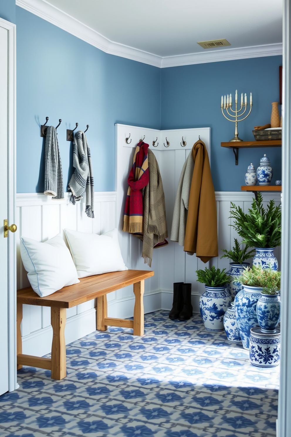 A serene mudroom featuring a blue and white color scheme. The walls are painted in a soft blue, complemented by white wainscoting and a patterned blue and white tile floor. A rustic wooden bench with white cushions sits against one wall, while hooks above it hold winter coats and scarves. Decorative elements include a festive Hanukkah menorah on a nearby shelf and a collection of blue and white ceramic pots with seasonal greenery.