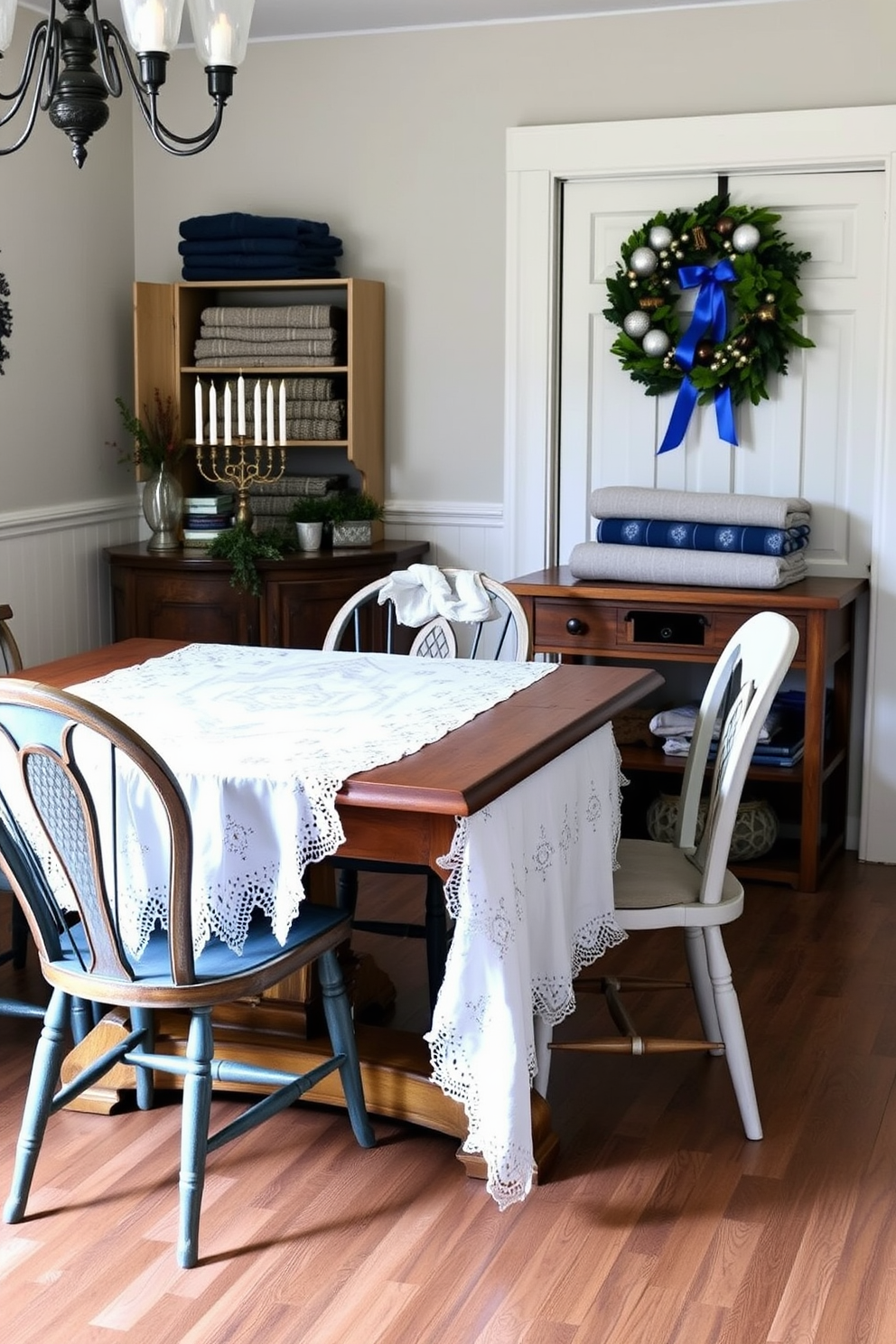 A white embroidered tablecloth drapes elegantly over a rustic wooden dining table, adorned with delicate lace edges that enhance its charm. Surrounding the table, mismatched vintage chairs add character, each featuring unique designs that complement the festive atmosphere. In the mudroom, a warm and inviting space is decorated for Hanukkah, featuring a menorah on a console table surrounded by blue and silver accents. Cozy woolen blankets are neatly folded on a shelf, while a cheerful wreath with blue ribbons hangs on the door, welcoming guests into the holiday spirit.