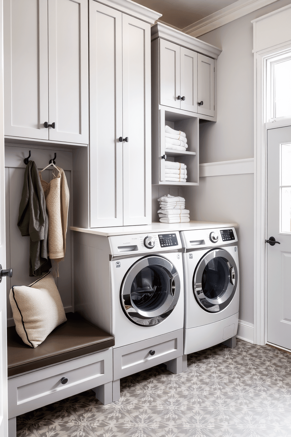 A stylish mudroom laundry room featuring maximized vertical storage with sleek cabinets that reach the ceiling. The cabinets are painted in a soft gray hue, providing a clean backdrop for decorative hooks and a bench with plush cushions below. On one side, a spacious washer and dryer are integrated into the cabinetry, surrounded by open shelving displaying neatly folded towels and laundry essentials. The floor is adorned with a durable, patterned tile that adds a pop of color and is easy to clean, while a large window allows natural light to brighten the space.