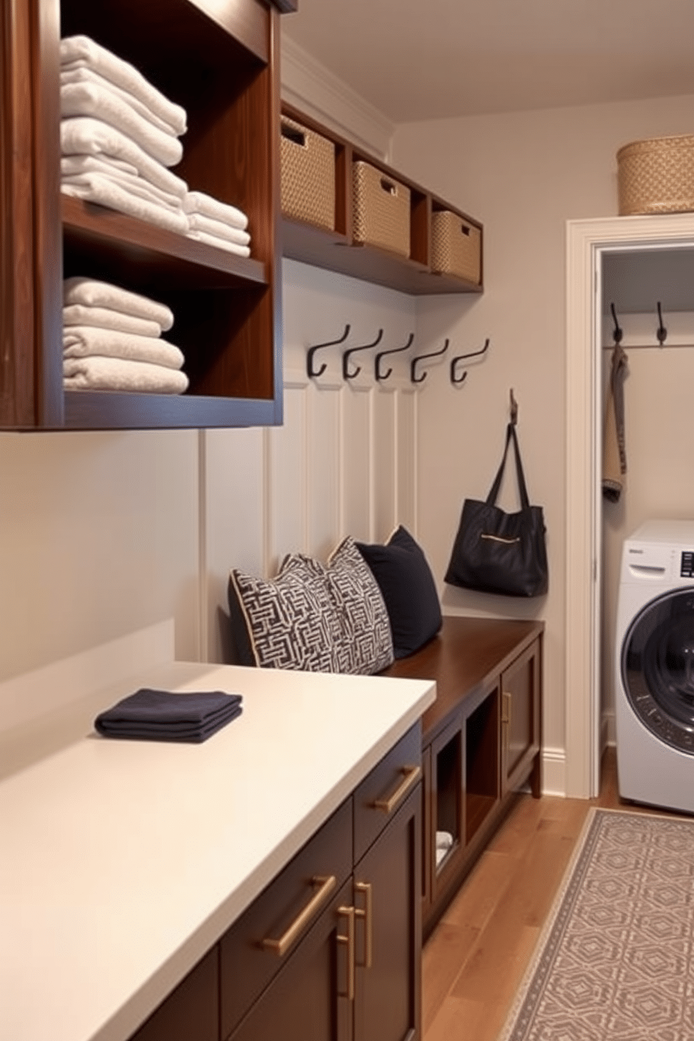 A sleek countertop designed for folding clothes is positioned against the wall, featuring a smooth, white surface that contrasts with the rich, dark cabinetry below. Above the countertop, open shelving displays neatly folded towels and decorative storage bins, creating an organized and inviting space. The mudroom laundry room combines functionality with style, featuring a built-in bench with plush cushions for comfortable seating. Stylish hooks line the wall for hanging coats and bags, while a patterned rug adds warmth and texture to the floor.