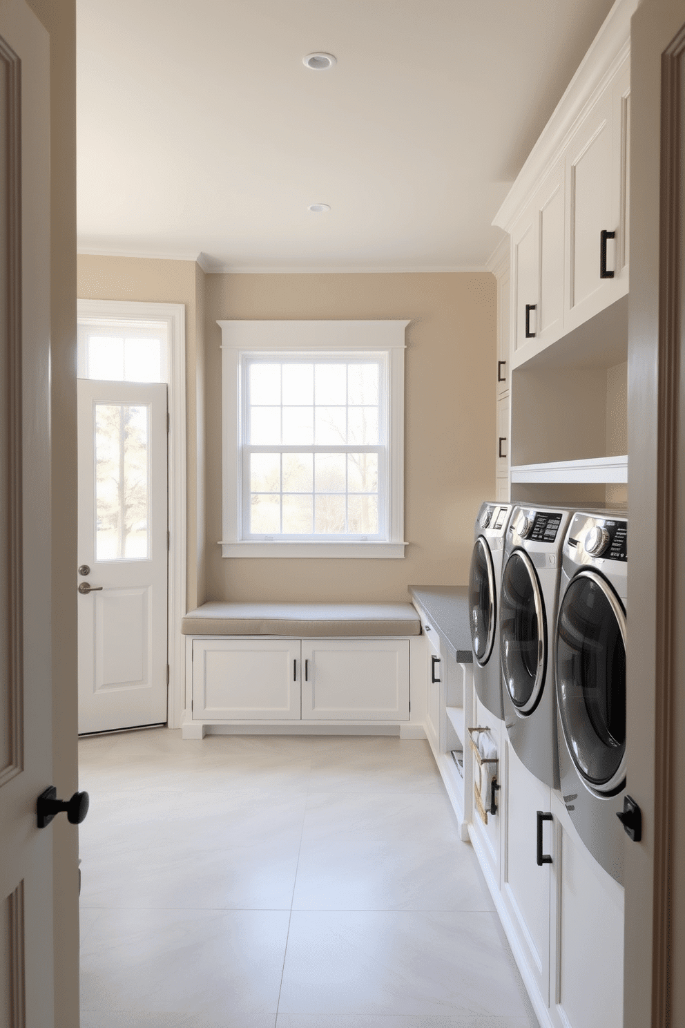 A serene mudroom laundry room featuring a neutral color palette that promotes a calming atmosphere. The walls are painted in soft beige, complemented by white cabinetry and a light gray countertop. A spacious built-in bench with storage underneath provides a functional yet stylish seating area. Natural light floods the space through a large window, highlighting the elegant ceramic tile flooring in a subtle pattern.