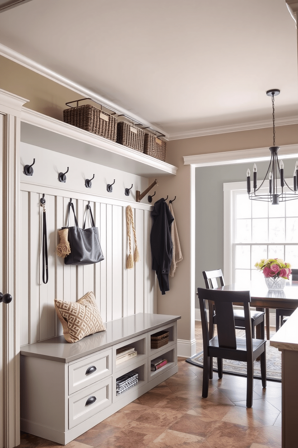 A functional drop zone for keys and mail features a built-in bench with storage underneath, providing a convenient place to sit while removing shoes. The walls are adorned with hooks for coats and bags, and a stylish wall-mounted shelf holds decorative baskets for organizing mail and small items. The mudroom near the dining room is designed with a cohesive color palette that complements the dining area. It includes a durable tile floor for easy cleaning, with a large window allowing natural light to brighten the space, creating an inviting transition between the two rooms.