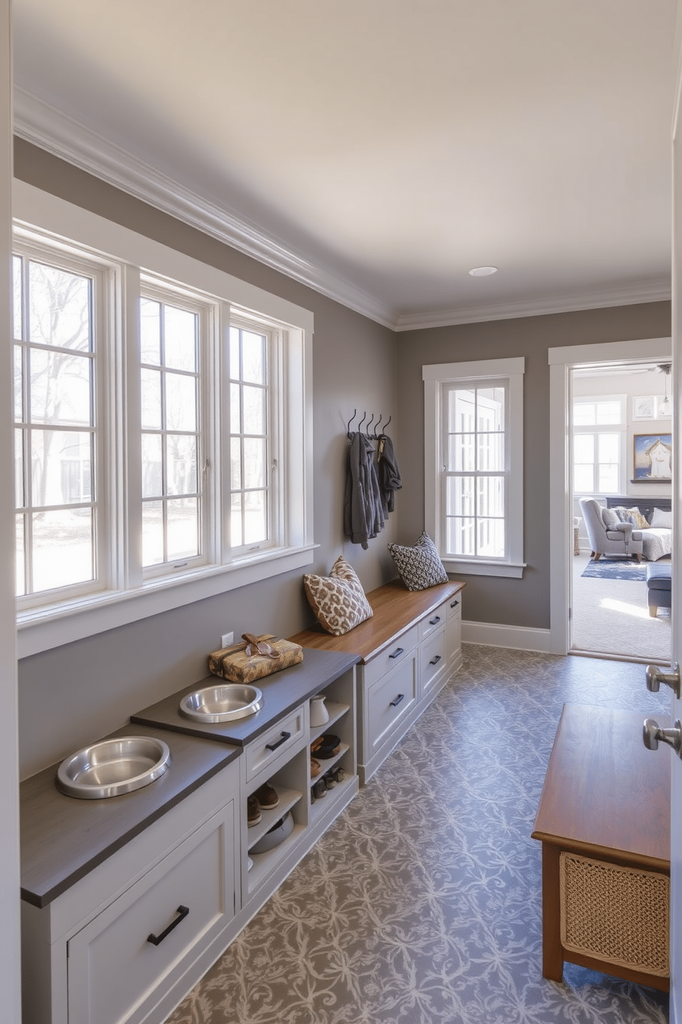 A cozy mudroom features a small pet station with a built-in feeding area, complete with stylish bowls and storage for pet supplies. The walls are painted a soft gray, and the floor is covered with durable, patterned tiles that can withstand muddy paws. Adjacent to the family room, the mudroom provides easy access with a bench for seating and hooks for coats and bags. Large windows allow natural light to flood the space, creating a welcoming transition between the indoors and outdoors.