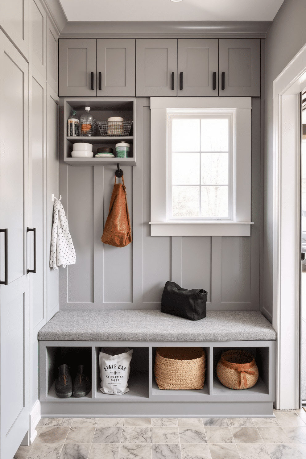 A functional mudroom near the garage features vertical storage for cleaning supplies, maximizing space efficiency. The walls are lined with sleek cabinetry in a soft gray finish, complemented by a durable, textured bench for seating.