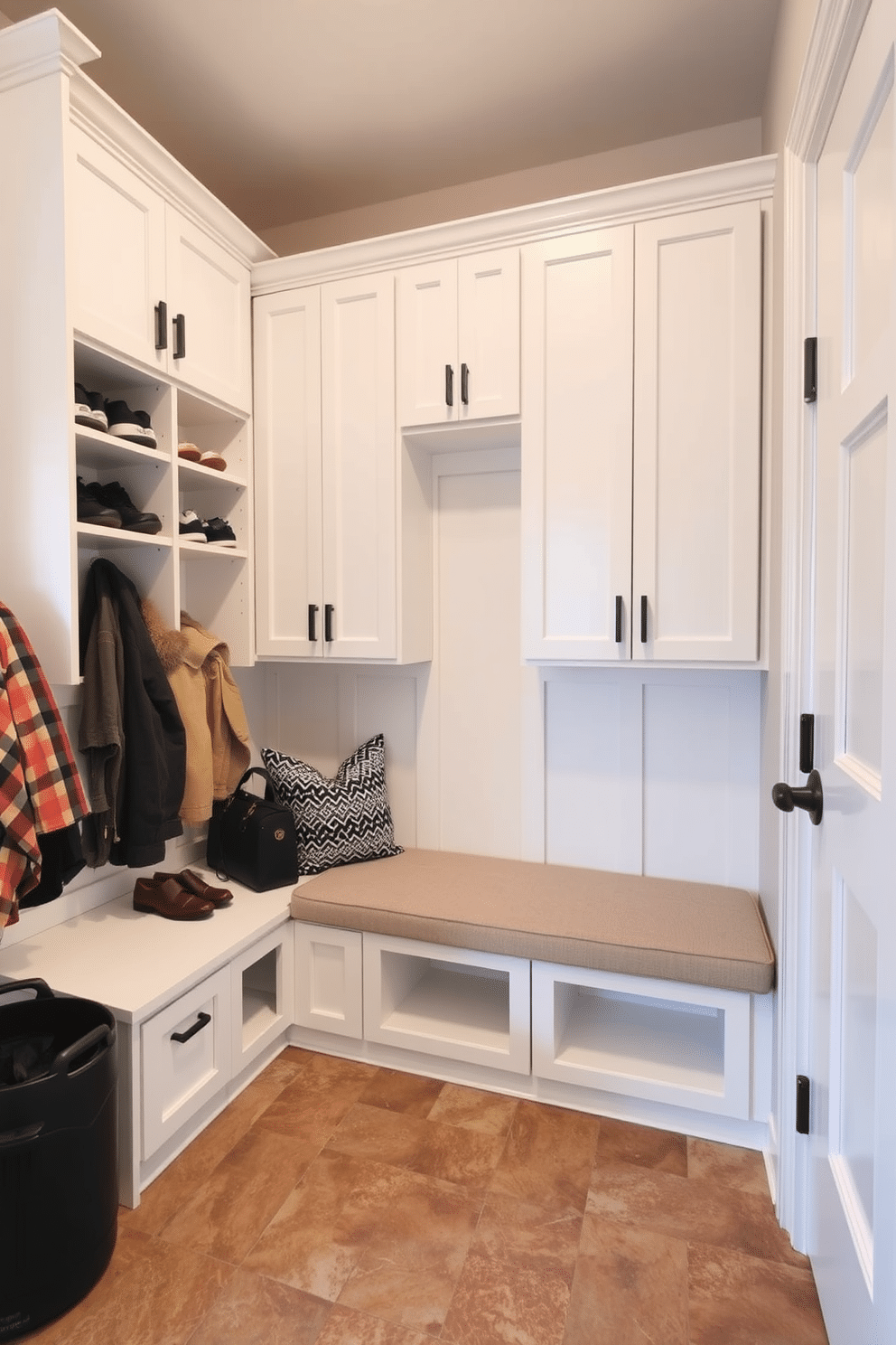 A functional mudroom near the garage features overhead cabinets in a crisp white finish, providing ample storage for shoes and outdoor gear. The space is accented with a durable, textured tile floor in earthy tones, complemented by a built-in bench with plush cushions for comfort.