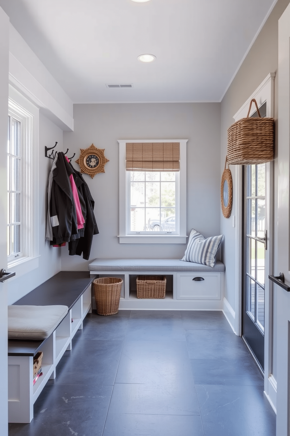 A stylish mudroom design near the garage features weather-resistant materials for durability and functionality. The space includes built-in storage benches with cushioned seats, hooks for coats, and a durable tile floor that can withstand heavy use. Natural light floods the room through a large window, highlighting a color palette of soft grays and whites. Accent elements such as woven baskets and decorative wall art add warmth and character to this practical entryway.