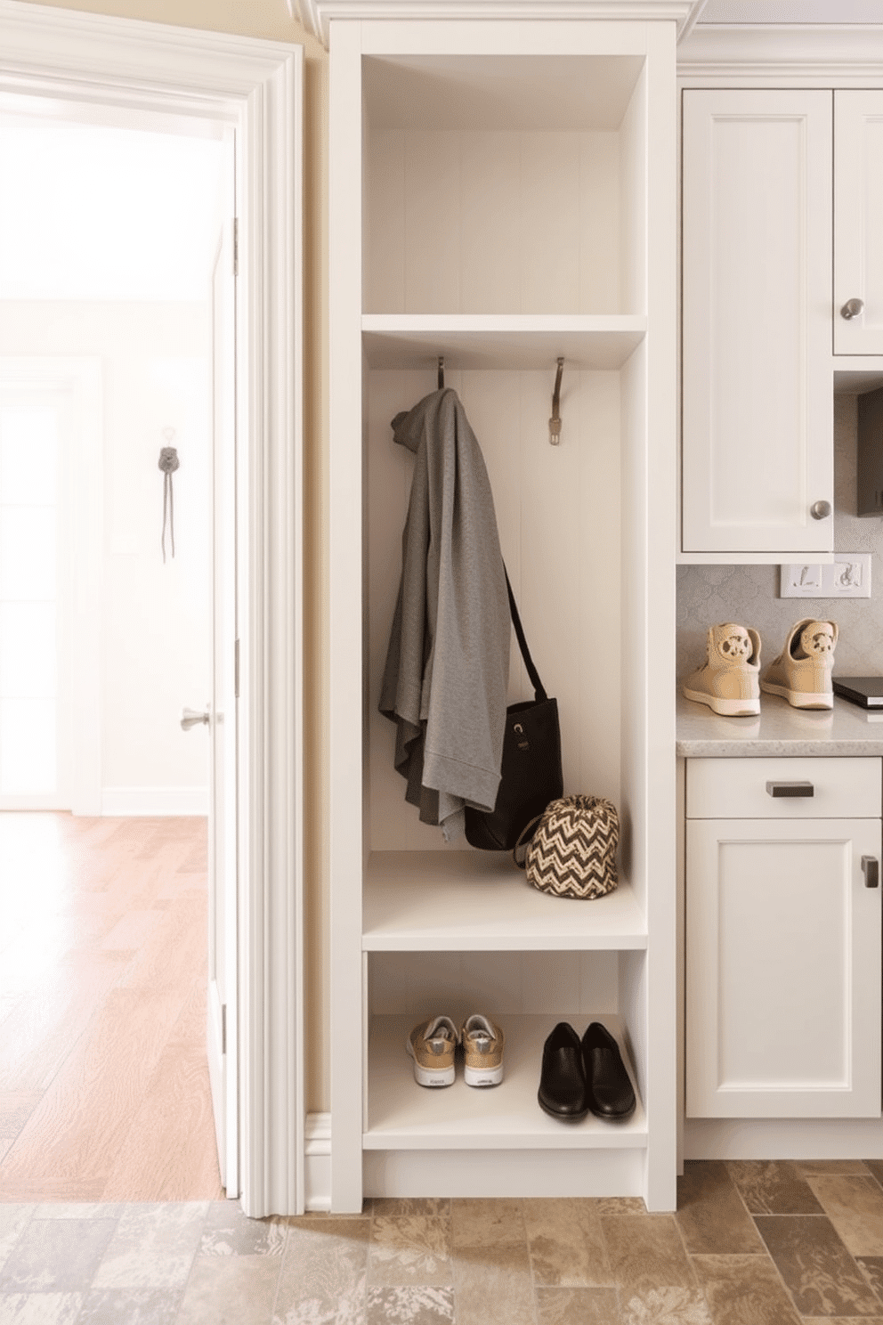 A functional mudroom adjacent to the kitchen features a wall-mounted drying rack for convenience, seamlessly integrated into the design. The space is adorned with built-in cabinetry in a soft white finish, providing ample storage for shoes and outdoor gear, while a durable, textured tile floor adds practicality and style.