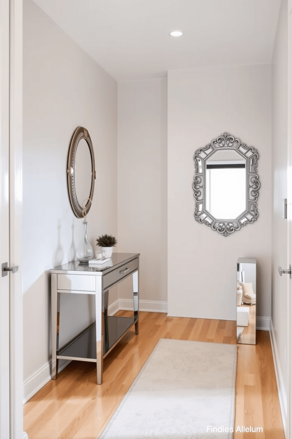 A narrow entryway features mirrored furniture that elegantly reflects light, creating an illusion of spaciousness. The walls are adorned with soft, neutral tones, and a sleek console table with a mirrored finish sits against one side, enhancing the airy feel of the space. On the opposite wall, a stylish mirror with an ornate frame adds depth and character, while a small potted plant brings a touch of greenery. The floor is finished with light hardwood, complemented by a chic runner rug that adds warmth and texture to the entryway.