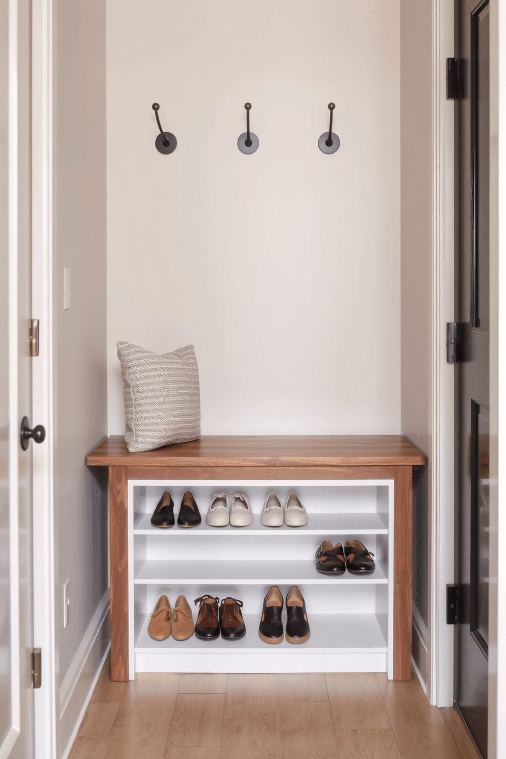 A narrow entryway featuring a stylish shoe rack seamlessly integrated beneath a sleek wooden bench. The walls are adorned with subtle textures and a soft color palette, while decorative hooks are mounted above for added functionality.