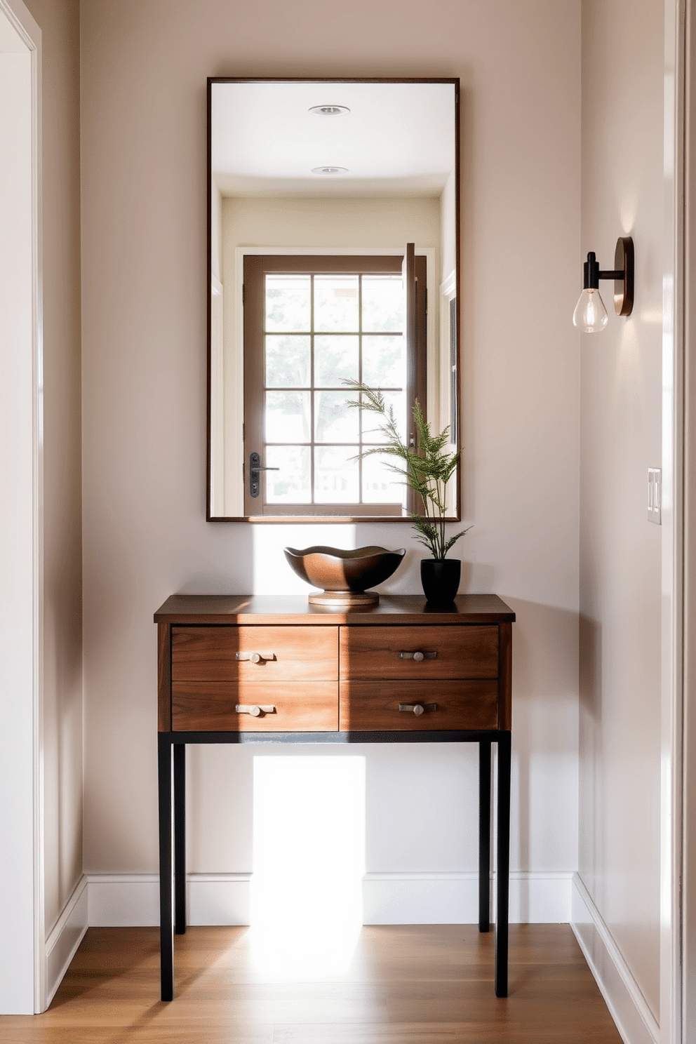 A functional entryway table with drawers is positioned against a soft gray wall, providing both style and storage. The table features a sleek wooden finish and is adorned with a decorative bowl and a small potted plant, adding a touch of greenery. In a narrow foyer, a narrow console table is elegantly placed, flanked by two stylish wall sconces that illuminate the space. The walls are painted in a light cream color, and a large mirror above the table reflects natural light, making the area feel more expansive.