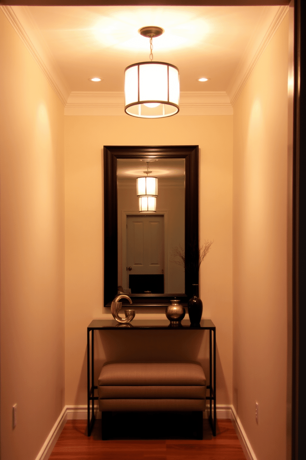 A narrow foyer featuring layered lighting to enhance both ambiance and functionality. The space is illuminated by a combination of recessed ceiling lights and a stylish pendant fixture, creating a warm and inviting atmosphere. The walls are painted in a soft, neutral tone, complemented by a slim console table adorned with decorative accents. A large mirror hangs above the table, reflecting light and creating the illusion of a larger space, while a small bench provides a convenient spot for seating.