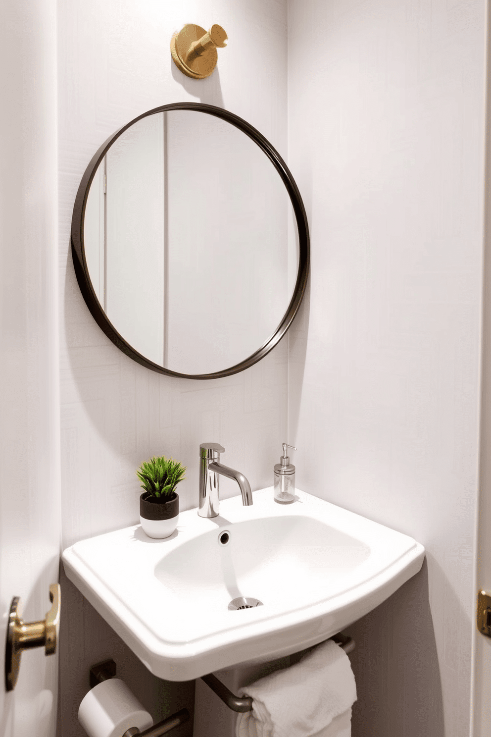 A narrow powder room features a corner sink to maximize floor space, elegantly designed with a sleek, wall-mounted faucet. The walls are adorned with a soft, light gray wallpaper, and a round mirror hangs above the sink, reflecting the stylish fixtures and a small potted plant on the countertop.