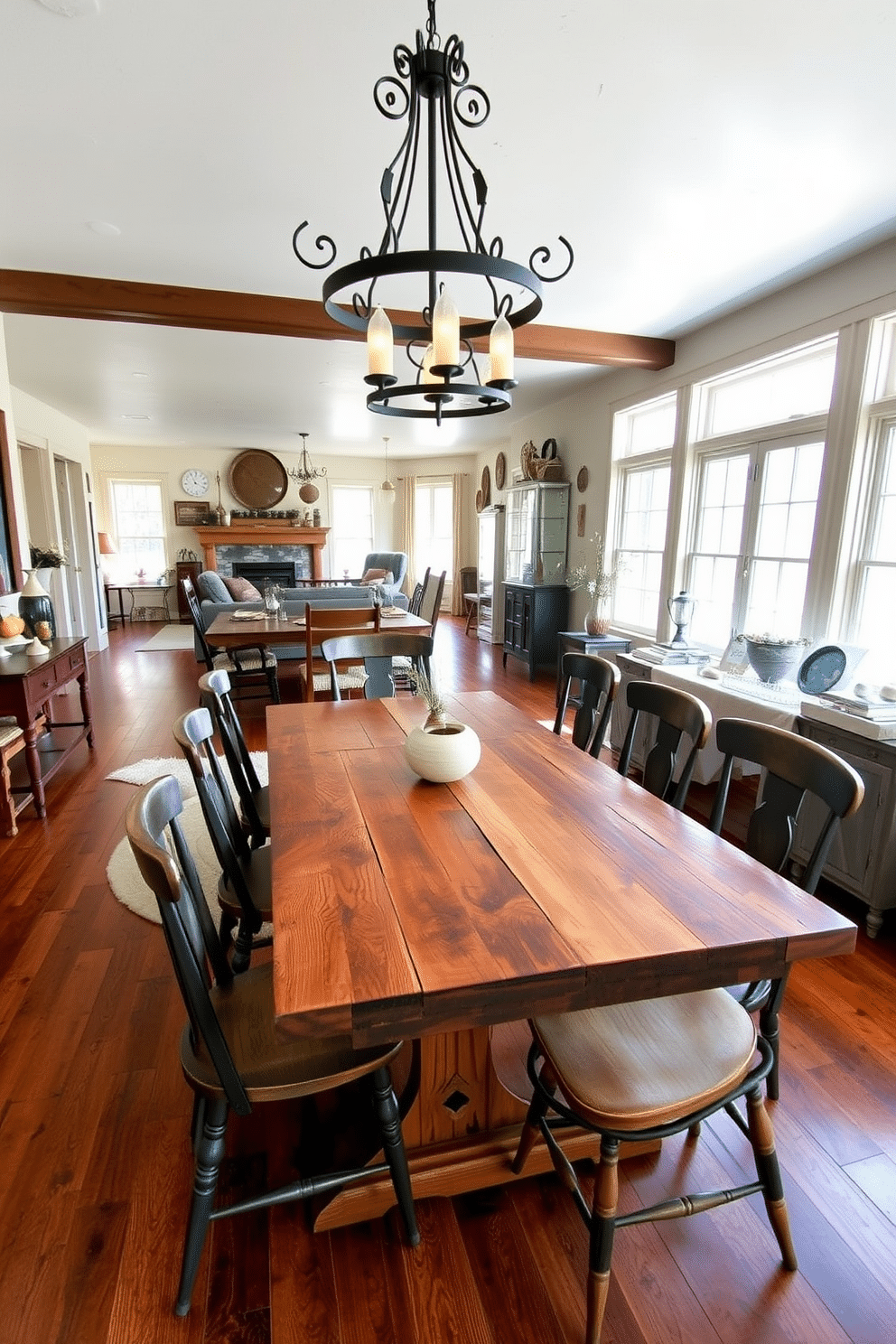 A rustic dining room features a reclaimed wood table surrounded by mismatched chairs, creating a warm and inviting atmosphere. Above the table, a wrought iron chandelier casts a soft glow, while the walls are adorned with vintage farmhouse decor. The open floor plan seamlessly integrates the dining area with the living space, allowing for easy flow and interaction. Large windows let in natural light, highlighting the warm tones of the wooden accents and the cozy textiles throughout the room.