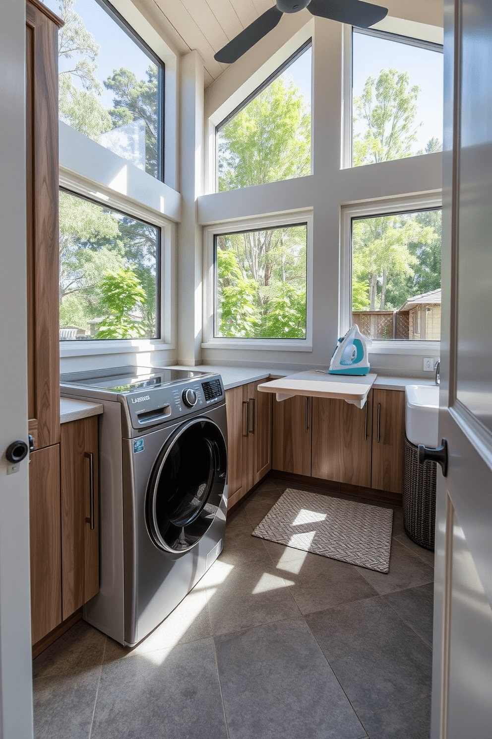 A modern outdoor laundry room featuring smart technology integration for enhanced convenience. The space includes a sleek washer and dryer with Wi-Fi connectivity, surrounded by custom cabinetry for storage and organization. Natural light floods in through large windows, illuminating a folding station with a built-in ironing board. The room is designed with durable, weather-resistant materials and includes a small sink for pre-washing delicate items.