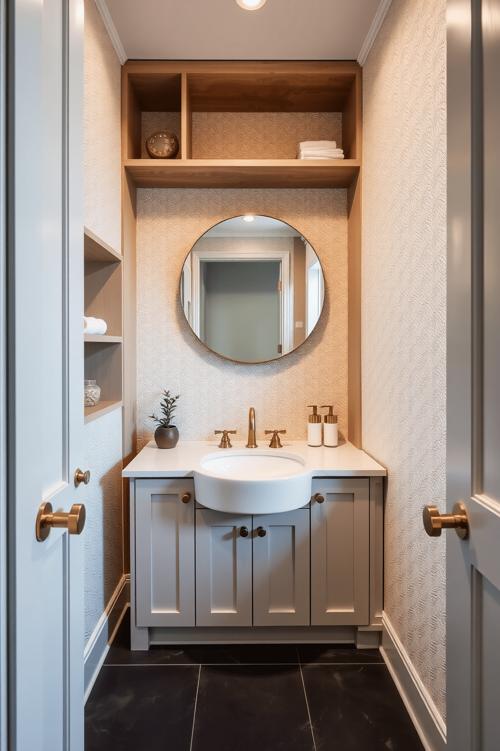 A stylish powder room featuring innovative built-in shelving that maximizes vertical space. The walls are adorned with a soft, textured wallpaper, and the floor is covered in sleek, dark tiles that contrast beautifully with the light fixtures. The custom-built vanity includes a unique sink design integrated into the cabinetry, creating a seamless look. Accents of brass hardware add a touch of elegance, while a large round mirror reflects the ambient light, enhancing the room's spacious feel.