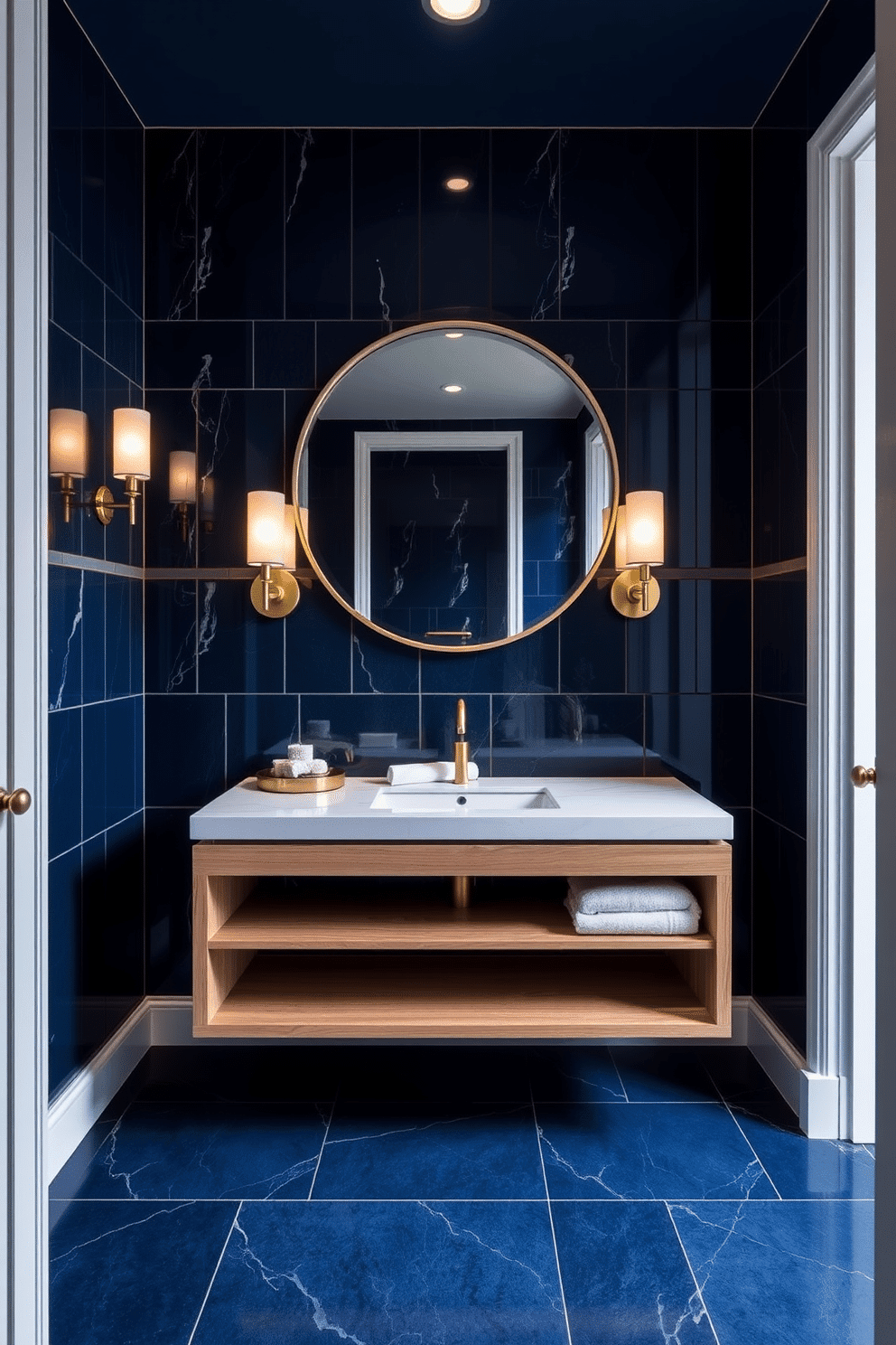 A luxurious powder room featuring floor-to-ceiling tiles in a rich, deep navy blue, creating a dramatic and grand effect. The space is accented with a sleek, modern floating vanity in a light oak finish, topped with a polished white marble countertop. Framed by elegant sconces, a large round mirror reflects the sophisticated design, enhancing the room's spacious feel. A stylish gold faucet stands out against the marble, while a plush white towel is neatly arranged on the vanity for a touch of comfort.