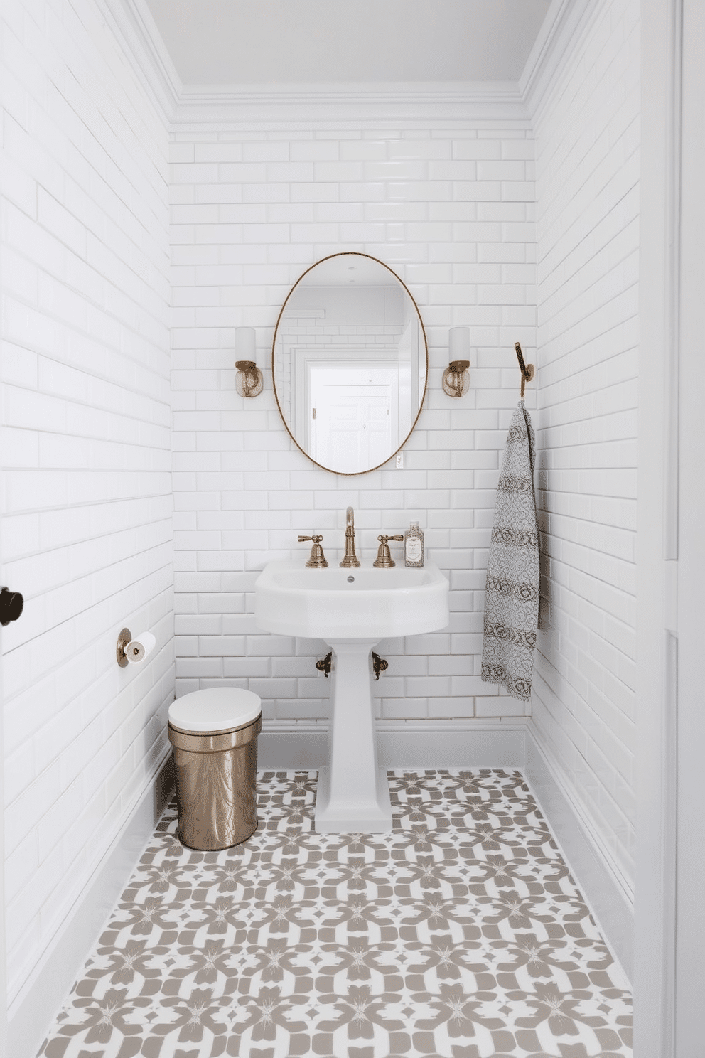 A chic powder room features classic white gloss subway tiles that create a timeless backdrop, extending from the floor to the ceiling. The floor is adorned with intricate geometric tiles in soft gray and white, adding a modern touch to the elegant space.