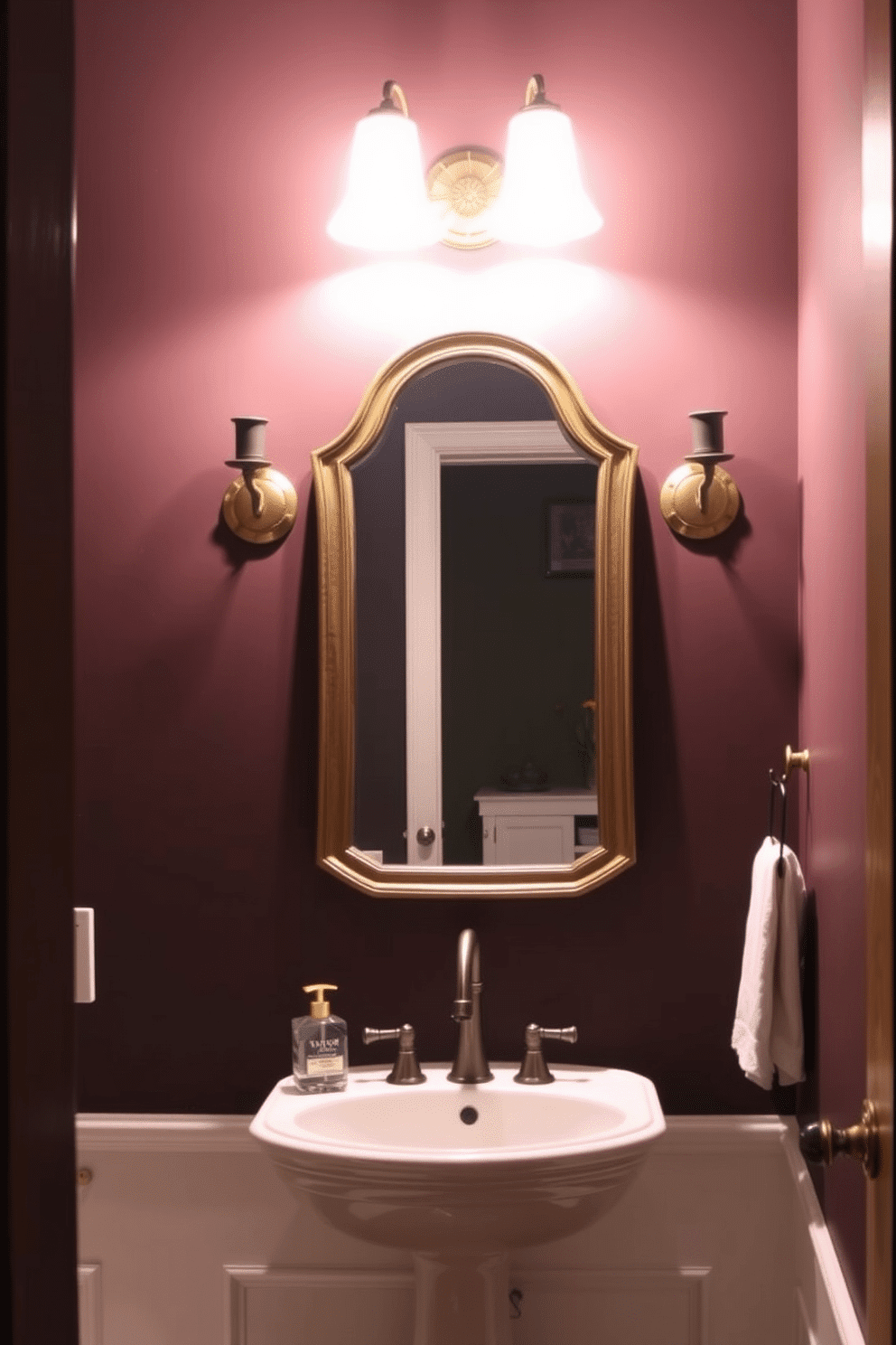 A stylish powder room featuring elegant sconce lighting that casts a warm glow. The sconces are mounted on either side of a vintage-style mirror, enhancing the classic ambiance of the space. The walls are adorned with a rich, deep color, creating a cozy backdrop for the well-lit room. A chic pedestal sink complements the overall design, with decorative accents adding a touch of sophistication.