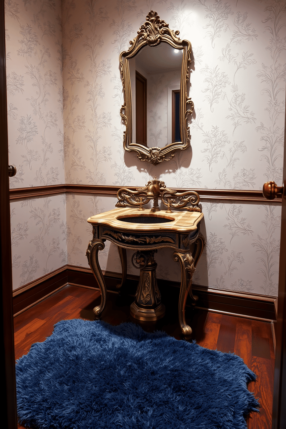 A stunning powder room featuring an antique sink with intricate detailing, showcasing ornate carvings and a distressed finish. The sink is paired with a vintage gold faucet, set against a backdrop of soft cream wallpaper adorned with delicate floral patterns. The floor is covered in rich mahogany tiles that add warmth to the space, while a small, elegant mirror with an antique frame hangs above the sink. A plush, deep blue rug lies beneath the sink, providing a pop of color and comfort in this refined setting.