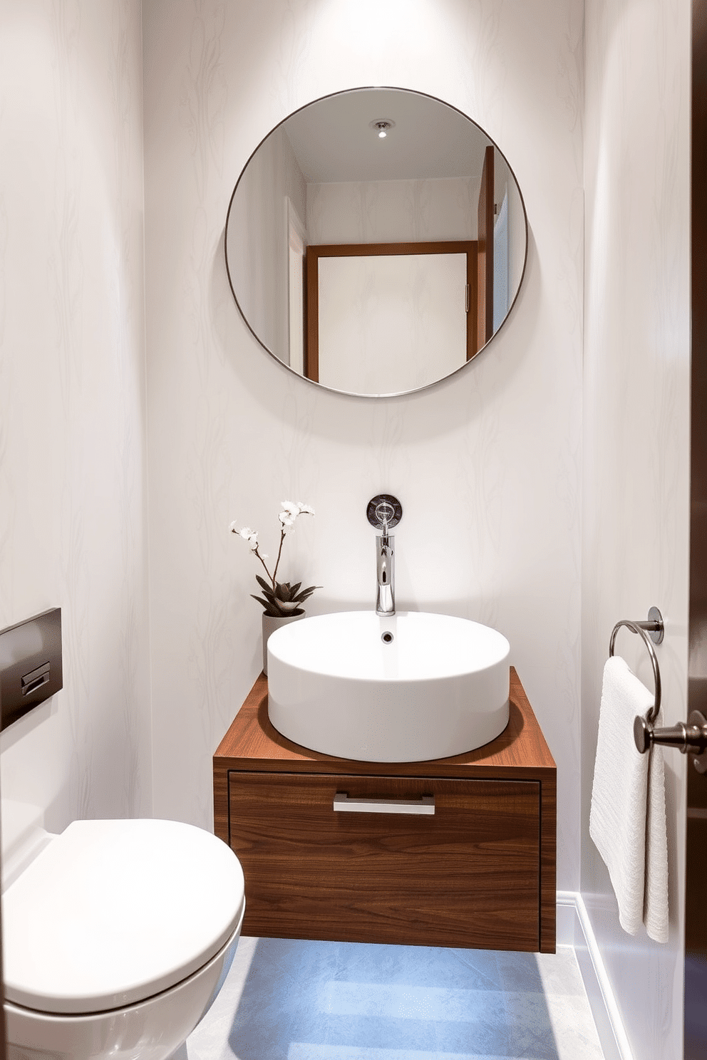 A chic powder room featuring a round sink with a sleek modern faucet that serves as the focal point. The walls are adorned with elegant wallpaper in soft pastel tones, complementing the minimalist design aesthetic. Beneath the sink, a floating vanity in a rich walnut finish provides ample storage while maintaining an airy feel. Accent lighting illuminates the space, highlighting decorative elements such as a small potted plant and a stylish hand towel.