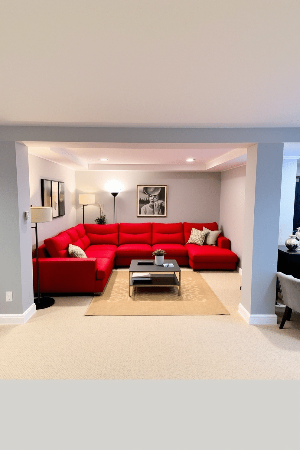 A modern red sectional sofa is the centerpiece of a stylish basement lounge, providing ample seating with its plush cushions and sleek lines. The surrounding walls are painted in a soft gray, creating a warm contrast that enhances the vibrant red of the furniture. The basement features an open layout with cozy nooks for relaxation, including a small reading corner with a contemporary floor lamp. Decorative elements like abstract art and a minimalist coffee table complete the inviting atmosphere.